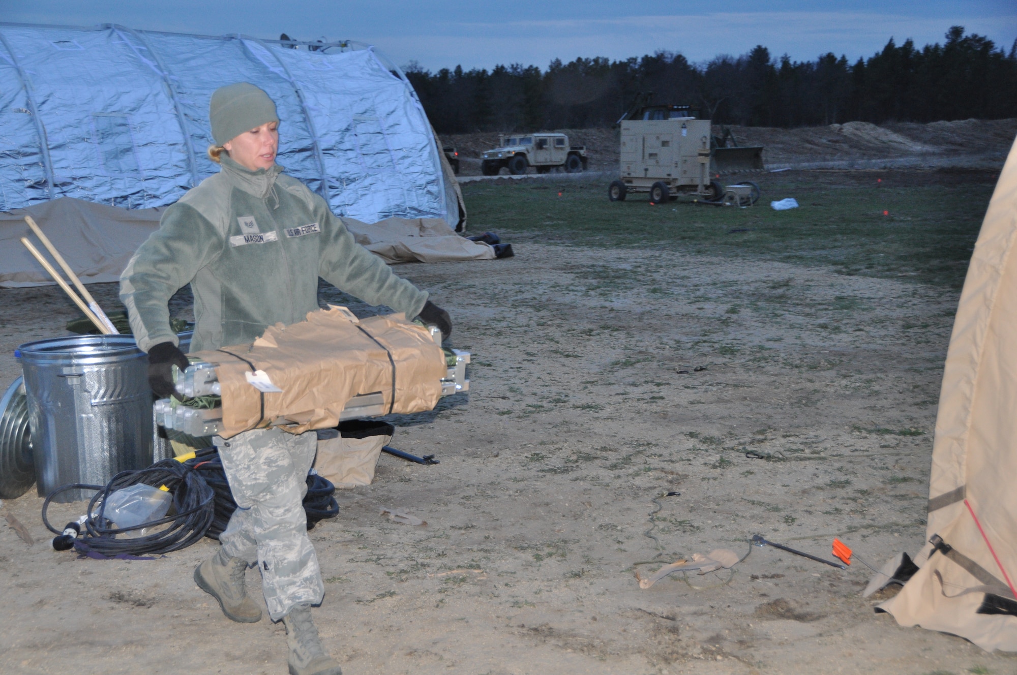 Staff Sgt. Sheri Mason from the 433rd Civil Engineer Squadron carries a cot into a tent in the chilly temperatures of Fort McCoy, Wis., April 26.   Air Force Reservists are preparing a Forward Operating Base in support of Exercise Patriot Warrior 2014. (U.S. Air Force photo by 1st Lt. Denise Haeussler)