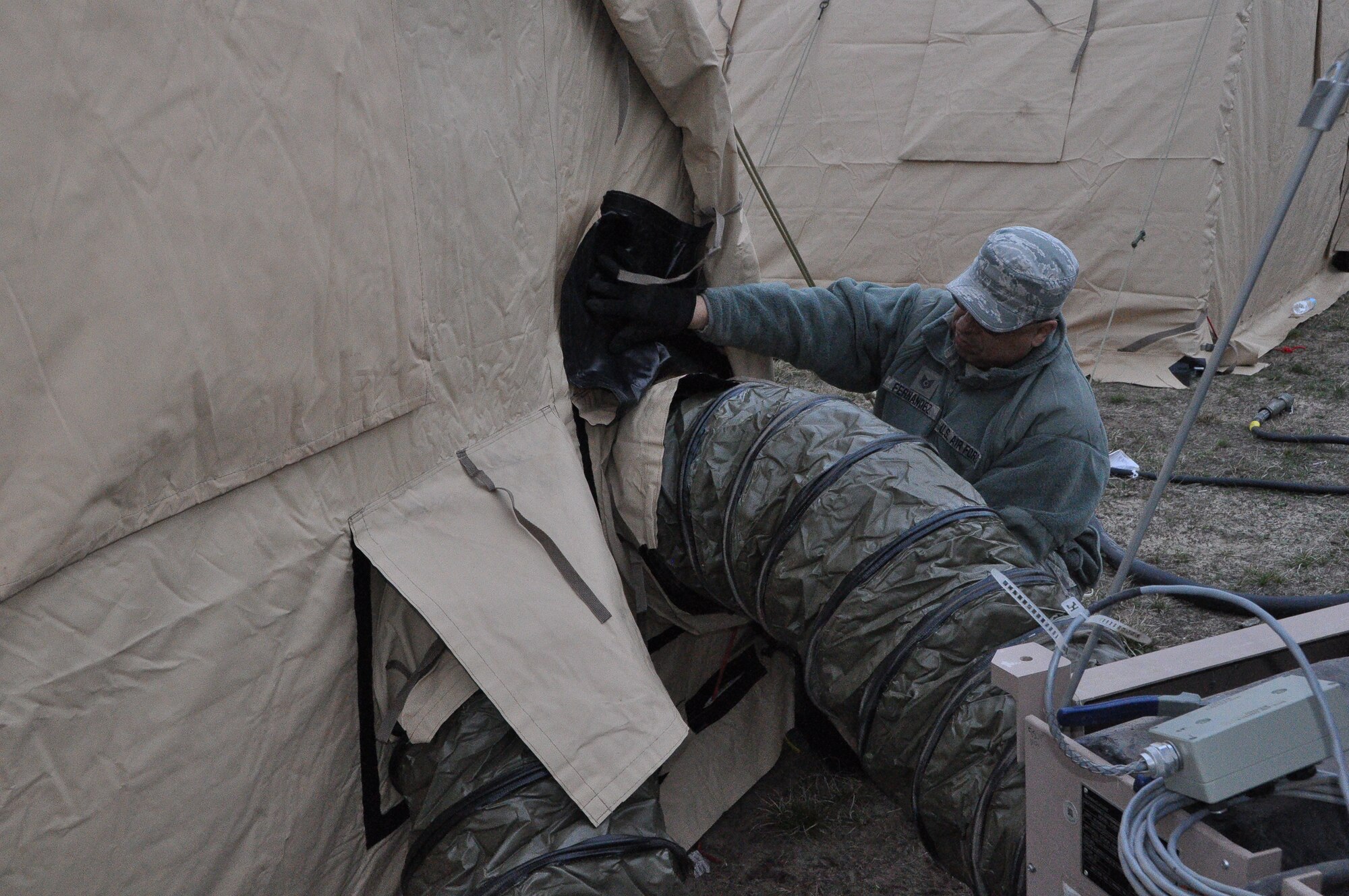 Tech. Sgt. Adrian Hernandez with the 433rd Civil Engineer Squadron hooks a generator into a tent as cold and darkness set in at Fort McCoy, Wis. April 26. The generator will provide heat and power to the living and working tents for Exercise Patriot Warrior 2014. (U.S. Air Force photo by 1st Lt. Denise Haeussler)