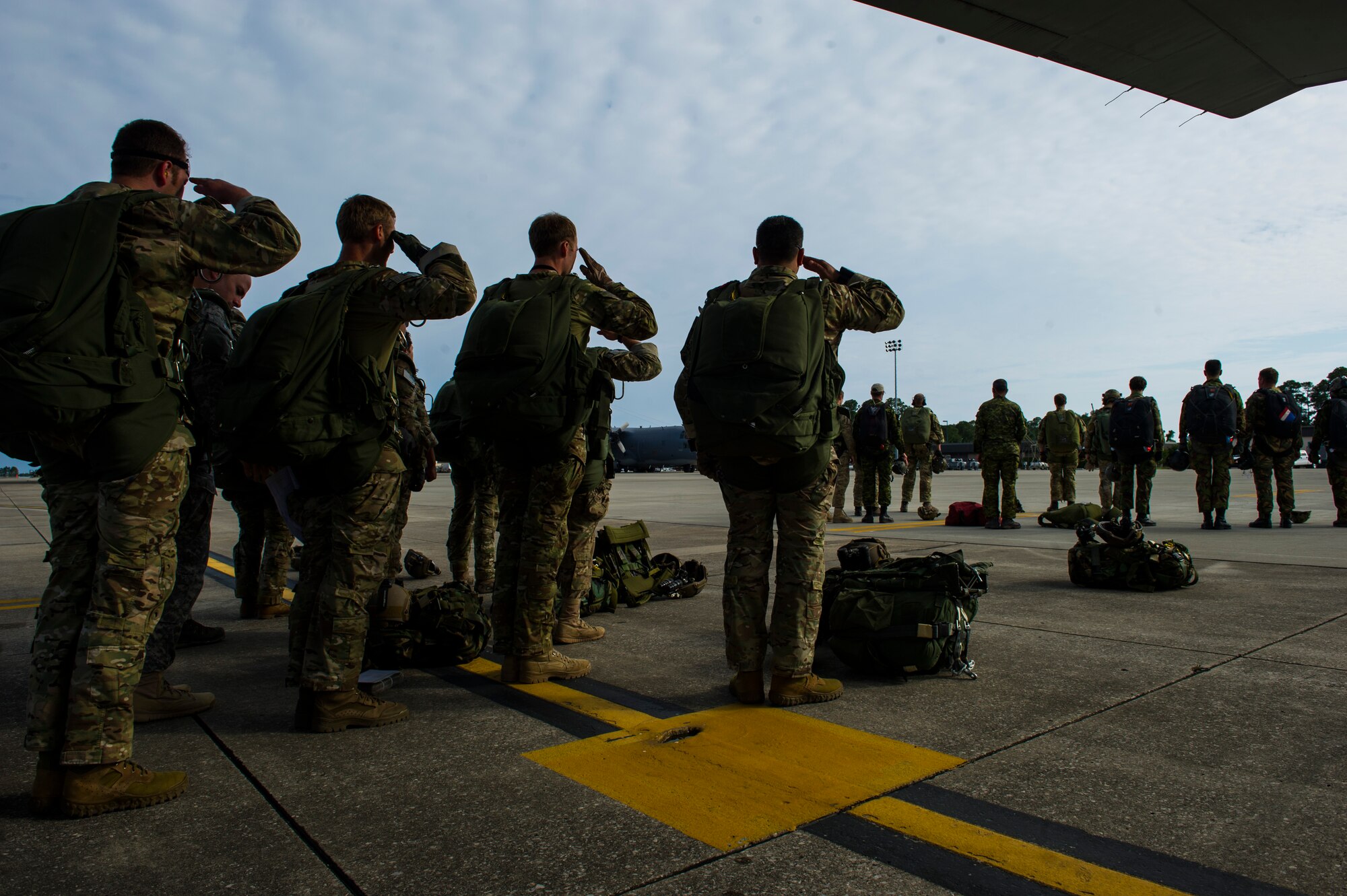 Members with the 7th Special Forces Group pause from preparing their parachutes for a high-altitude low-opening jump to pay their respects during retreat on Hurlburt Field, Fla., May 2, 2014. Emerald Warrior is an annual, joint exercise to train special operations, conventional and partner nation forces in combat scenarios designed to hone special operations air and ground combat skills, and is the Department of Defense's only irregular warfare exercise. (U.S. Air Force photo by Staff Sgt. Marleah Miller)