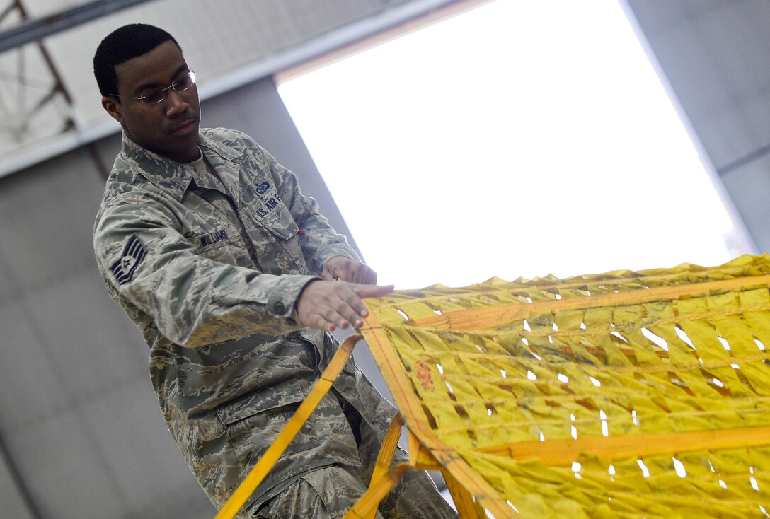 Staff Sgt. John Williams, 5th Operations Support Squadron aircrew flight equipment technician assigned to Minot Air Force Base, N.D. and on temporary duty at Ellsworth, spreads out a drag parachute for a B-52 Stratofortress at Ellsworth Air Force Base, S.D., April 30, 2014. A drag chute is an extra large parachute that B-52 aircrews deploy during landing to slow the aircraft’s momentum. (U.S. Air Force photo by Senior Airman Zachary Hada/Released)