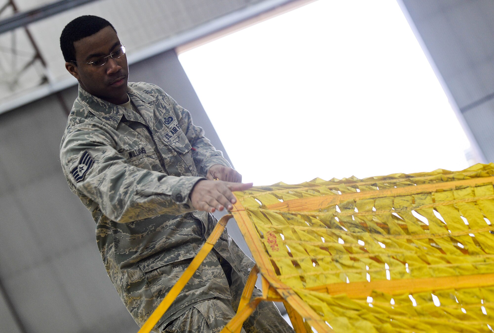 Staff Sgt. John Williams, 5th Operations Support Squadron aircrew flight equipment technician assigned to Minot Air Force Base, N.D. and on temporary duty at Ellsworth, spreads out a drag parachute for a B-52 Stratofortress at Ellsworth Air Force Base, S.D., April 30, 2014. A drag chute is an extra large parachute that B-52 aircrews deploy during landing to slow the aircraft’s momentum. (U.S. Air Force photo by Senior Airman Zachary Hada/Released)