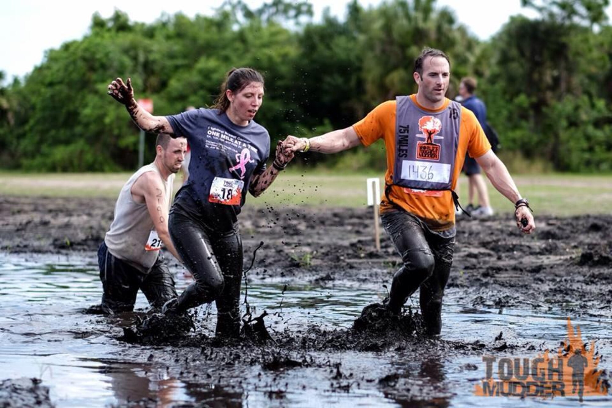 Master Sgt. Sherri Moore navigates a mud hole obstacle with the help of a friend during the Tough Mudder competition. This particular obstacle is full of soft mud and deep holes, causing quite a conundrum for competitors. (Photo courtesy of Tough Mudder)