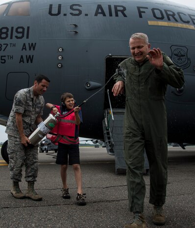 Col. Darren Hartford gets sprayed by his son Matthew with the assistance of Staff Sgt. David Glowacki, 437th Operations Support Squadron weather forecaster, after finishing his final flight as the 437th Airlift Wing commander May 5 2014, on the flightline at Joint Base Charleston, S.C. The final or "fini flight," is an aviation tradition in which aircrew members are met by their unit comrades, family and friends and soaked with water. (U.S. Air Force photo/ Airman 1st Class Clayton Cupit)