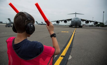 Matthew Hartford, Col. Darren Hartford’s son, marshals in a C-17 Globemaster III with the assistance of an Airman May 5, 2014, on the flightline at Joint Base Charleston, S.C. Hartford was piloting the C-17 for his final flight as the 437th Airlift Wing commander. The final or "fini flight," is an aviation tradition in which aircrew members are met by their unit comrades, family and friends and soaked with water. (U.S. Air Force photo/ Airman 1st Class Clayton Cupit)