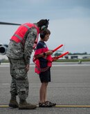 An Airman teaches Matthew Hartford, Col. Darren Hartford’s son, about marshalling techniques May 5, 2014, on the flightline at Joint Base Charleston, S.C. Hartford was piloting a C-17 Globemaster III for his final flight as the 437th Airlift Wing commander. The final or "fini flight," is an aviation tradition in which aircrew members are met by their unit comrades, family and friends and soaked with water. (U.S. Air Force photo/ Airman 1st Class Clayton Cupit)