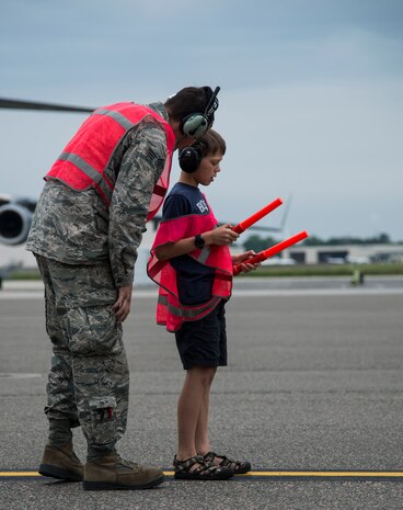 An Airman teaches Matthew Hartford, Col. Darren Hartford’s son, about marshalling techniques May 5, 2014, on the flightline at Joint Base Charleston, S.C. Hartford was piloting a C-17 Globemaster III for his final flight as the 437th Airlift Wing commander. The final or "fini flight," is an aviation tradition in which aircrew members are met by their unit comrades, family and friends and soaked with water. (U.S. Air Force photo/ Airman 1st Class Clayton Cupit)