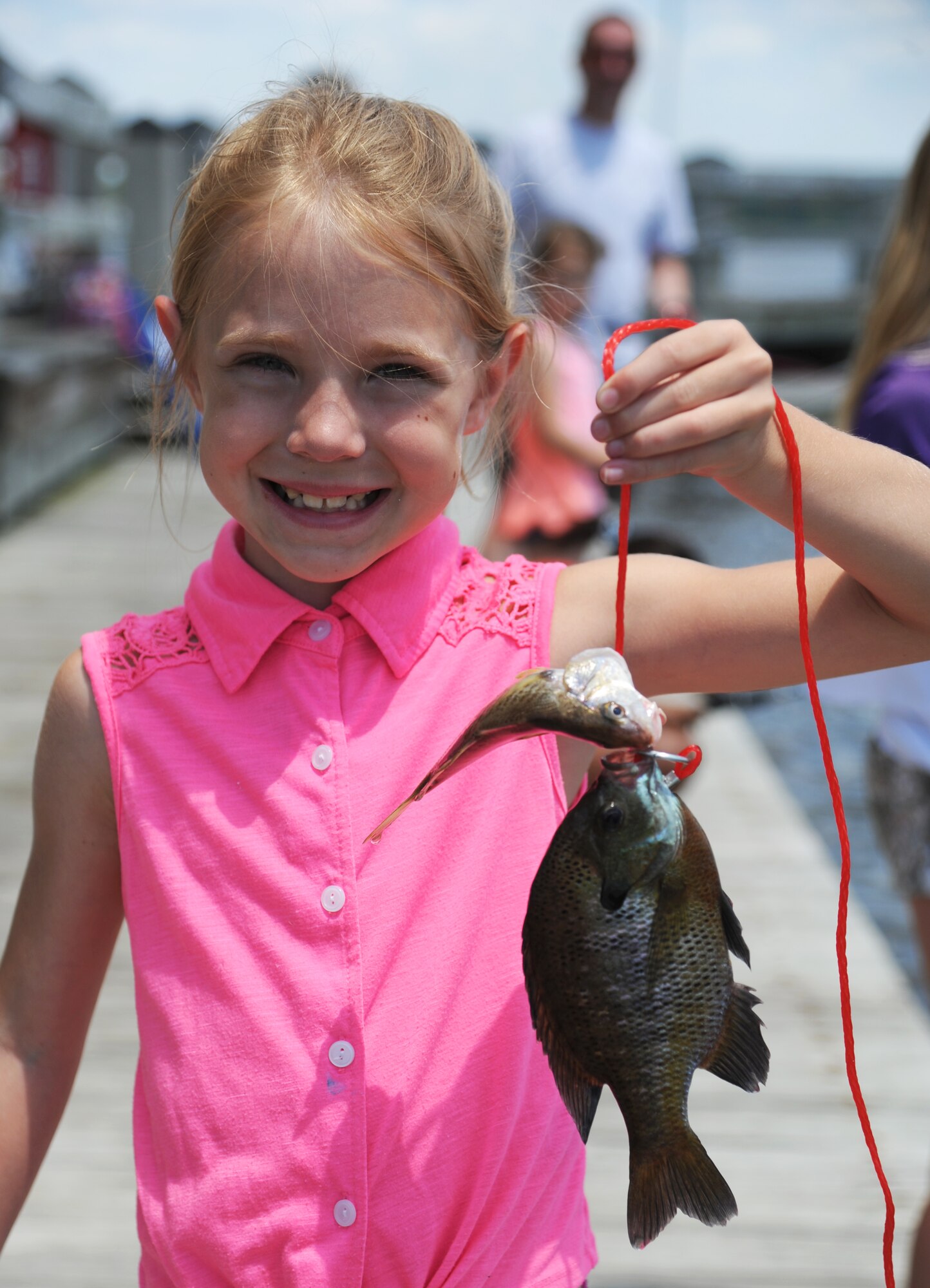The daughter of Troy Kirkbride, 334th Training Squadron, proudly displays a couple of fish she caught during the Kids Spring Fishing Rodeo May 3, 2014, at the marina, Keesler Air Force Base, Miss.  The event was hosted by the outdoor recreation center. (U.S. Air Force photo by Kemberly Groue)