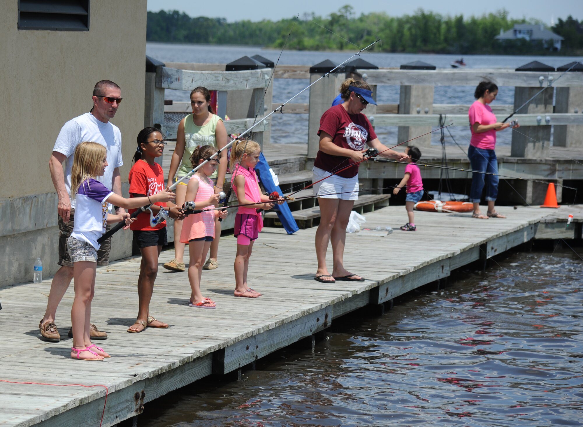 Troy Kirkbride, (left), 334th Training Squadron, along with his family and friends’ children fish off of the Keesler Marina pier during the Kids Spring Fishing Rodeo May 3, 2014, at Keesler Air Force Base, Miss.  The event was hosted by the outdoor recreation center. (U.S. Air Force photo by Kemberly Groue)