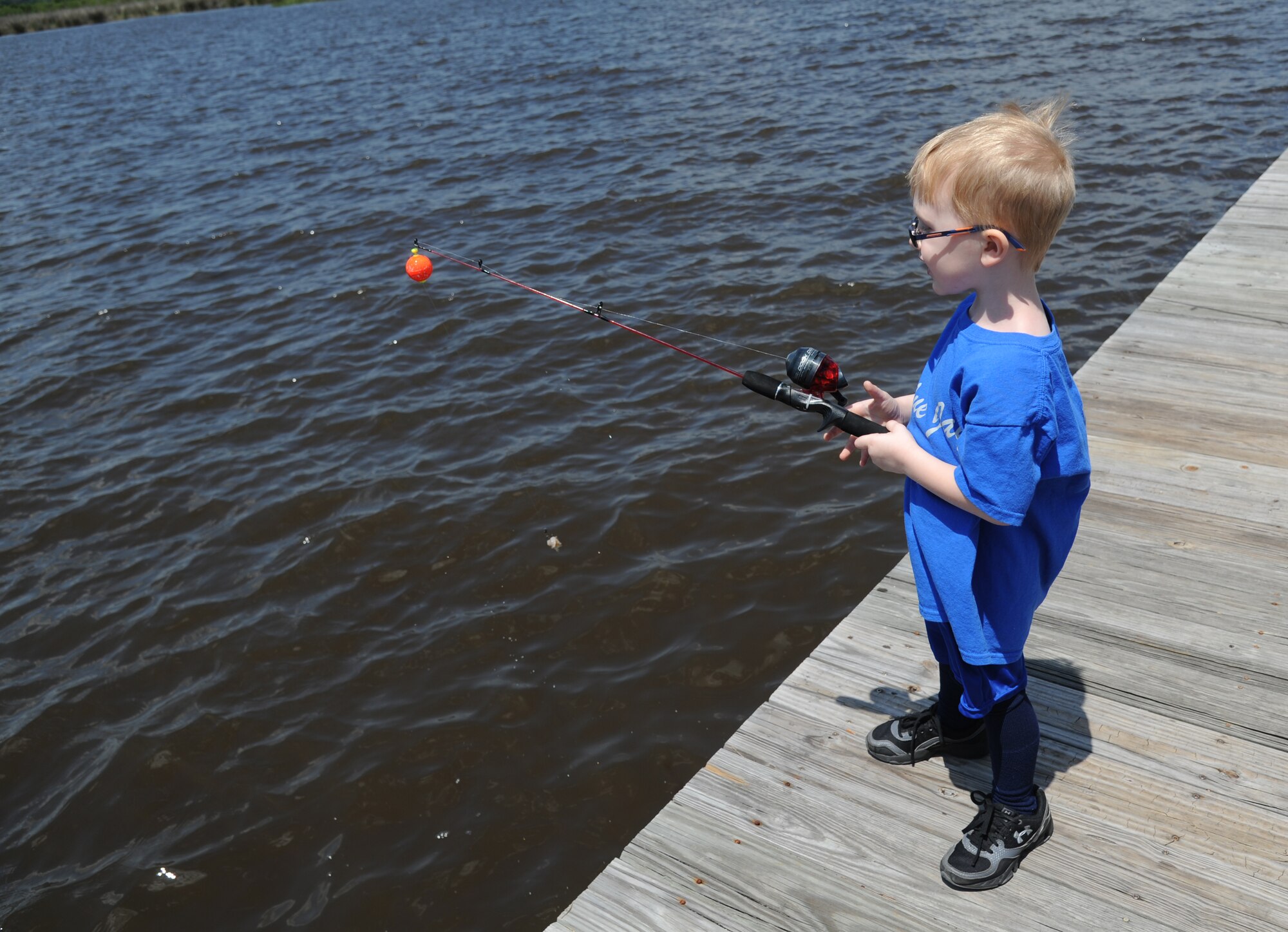 The son of Marine Sgt. Christopher Smith, Keesler Marine Detachment, reels in his fishing line to inspect his bait during the Kids Spring Fishing Rodeo May 3, 2014, at the marina, Keesler Air Force Base, Miss.  The event was hosted by the outdoor recreation center. (U.S. Air Force photo by Kemberly Groue)