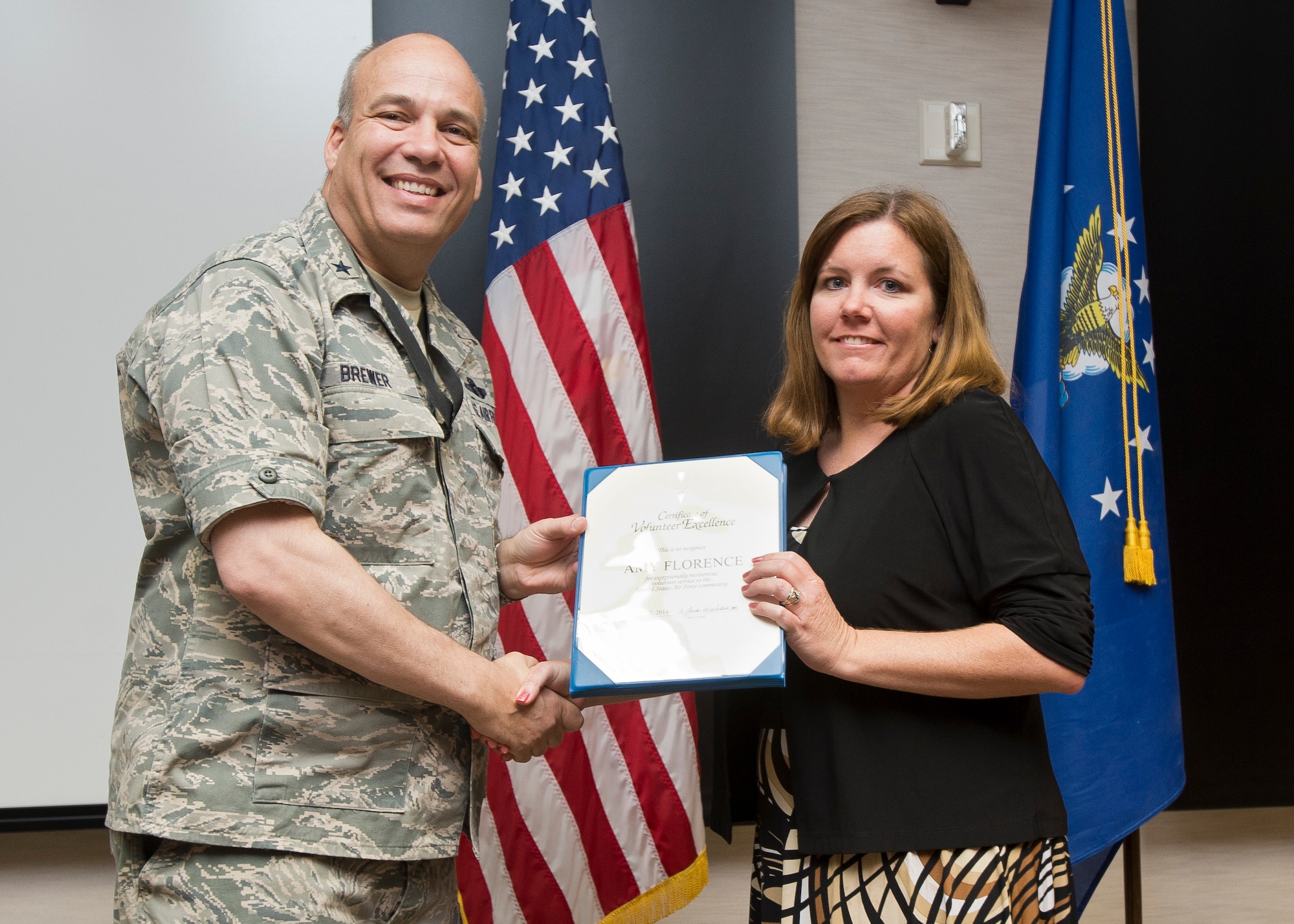 Brig. Gen. Michael Brewer, 412th Test Wing commander, presents Amy Florence with the Air Force Volunteer Excellence Award for her work with the Joint Strike Fighter Operational Test Team and Branch Elementary School. (U.S. Air Force photo by Ethan Wagner)