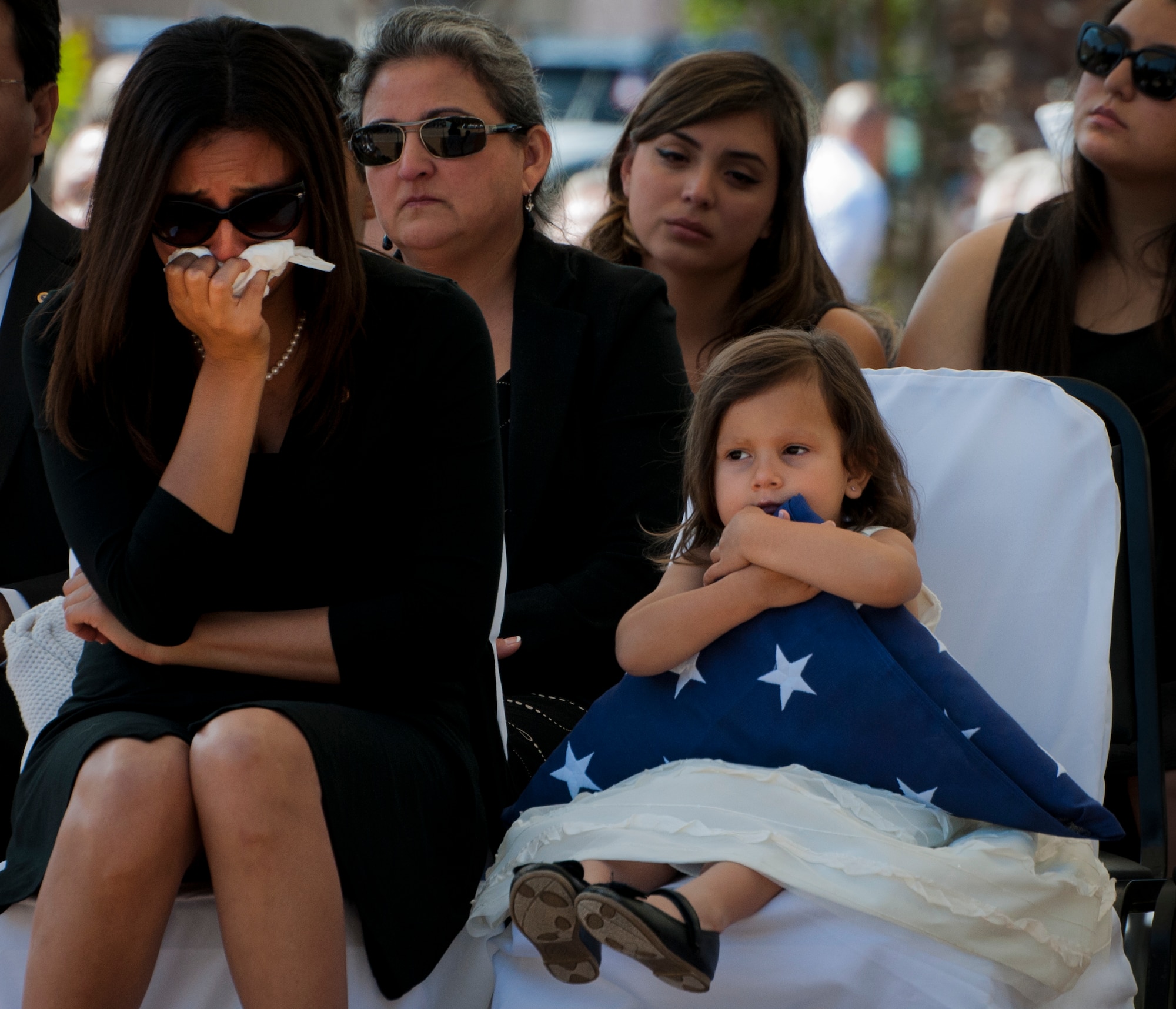 Vicki Baker, widow of Sgt. 1st Class Jeffrey Baker, weeps while their daughter, Audrey, holds a flag presented to her during the 45th Annual Explosive Ordnance Disposal Memorial Ceremony May 3, at Eglin Air Force Base, Fla. Eight new names of Army and Marine EOD technicians, who lost their lives, were added to the Memorial Wall this year.  The all-service total now stands at 306. (U.S. Air Force photo/Tech. Sgt. Sam King)