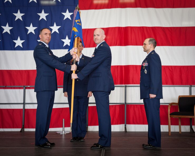 Col. Michael Burns (left), 934th Mission Support commander, presents the 27th Aerial Port guidon to Maj. Edward Buck (center).  Maj. Buck assumed command of the 27th Aerial Port Squadron from former commander Lt. Col. Michael Deselich (right) during a Change of Command ceremony Saturday of the May Unit Training Assembly weekend at Minneapolis-St. Paul Air Reserve Station, Minn.  (U.S. Air Force photo by Shannon McKay/Released)