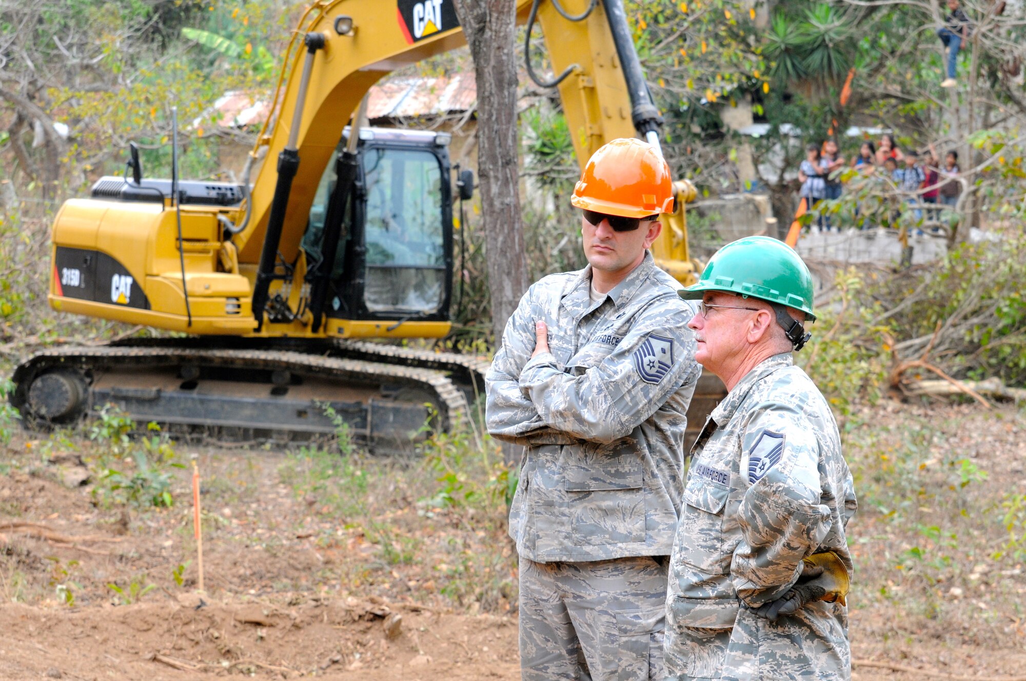 Guatemalan children watch from a nearby tree as Master Sgt. Larry Ricketts discusses construction with Master Sgt. Joshua Rich, 188th Civil Engineer Squadron fist sergeant, during Beyond the Horizon 2014 on April 8. Both Airmen are assigned to the 188th Fighter Wing’s Civil Engineer Squadron, Arkansas Air National Guard. U.S. Army South is partnering with Guatemala to execute Beyond the Horizon, a focused humanitarian assistance operation conducting various engineering assistance, medical, dental and civic action programs. (U.S. Army National Guard photo by Lt. Col. Richard D. Garringer/released)
