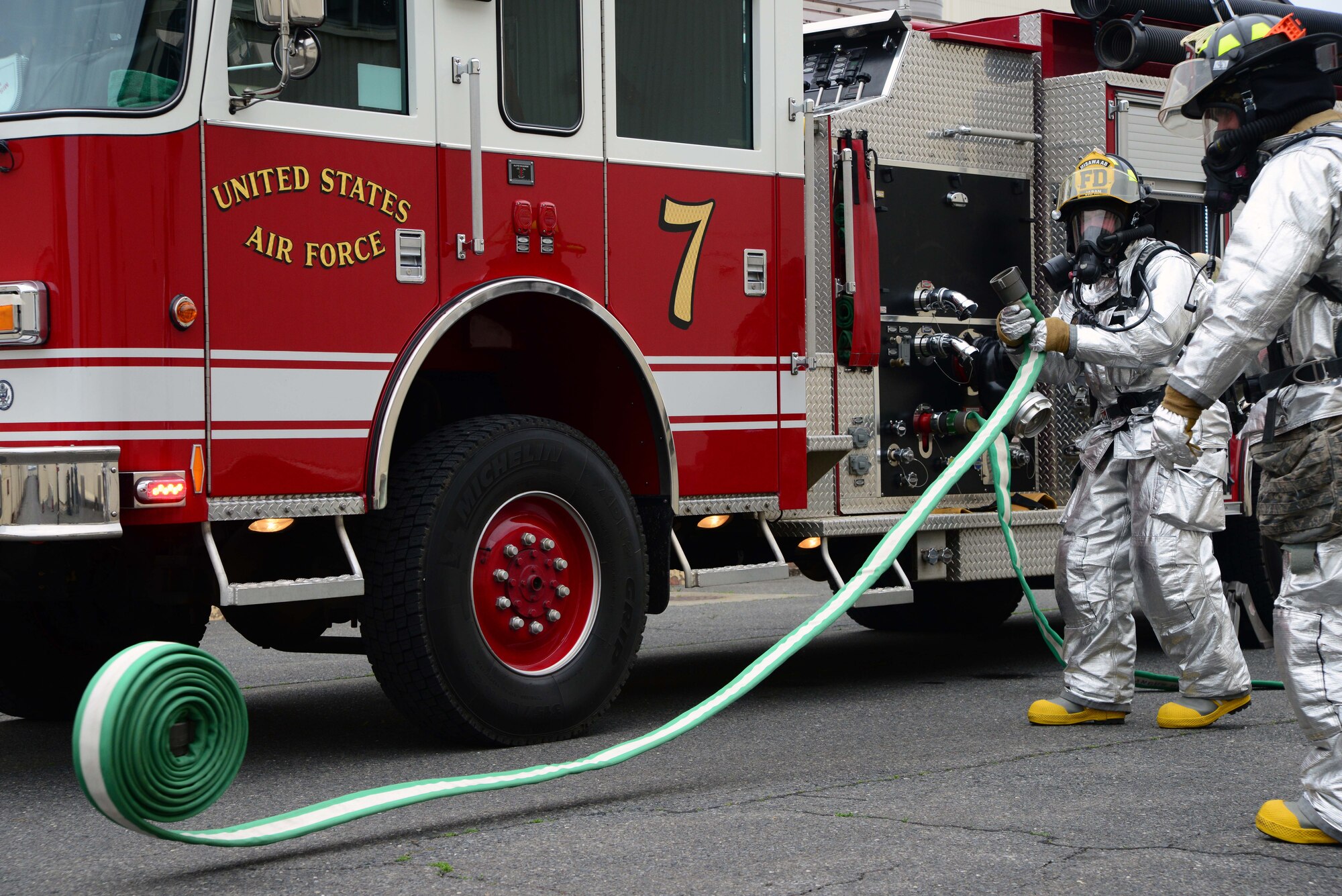 Two U.S. Air Force firefighters from the 35th Civil Engineer Squadron roll out water hoses to combat a simulated hangar fire during an Operational Readiness Exercise at Misawa Air Base, Japan, May 5, 2014. Firefighters faced a missile attack which forced them to extinguish a fire and perform Self-Aid Buddy Care on injured Airmen. (U.S. Air Force photo/Senior Airman Derek VanHorn)