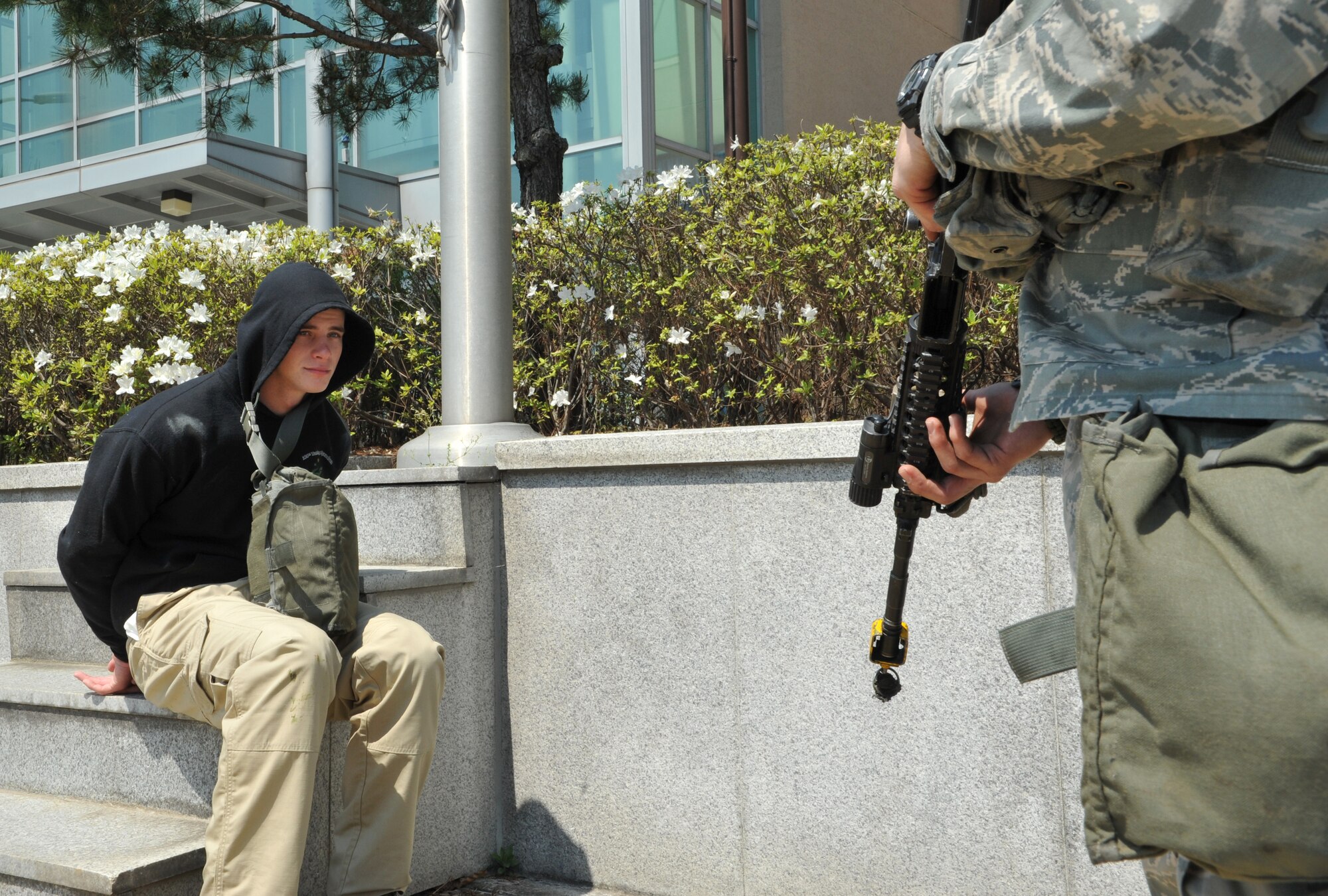 Airman 1st Class Cody Linday, left, 51st Security Forces Squadron entry controller, acts as a detained member of opposition forces while A1C David Diez, 51st SFS entry controller, guards him during Operational Readiness Exercise Beverly Bulldog 14-02 at Osan Air Base, Republic of Korea, May 5, 2014. Staff Sgt. Juan Valles, 51st SFS area supervisor, was also part of the training scenario that required himself and Diez to wait for Office of Special Investigations personnel to reach the scene and interrogate their detainee. (U.S. Air Force photo/Airman 1st Class Ashley J. Thum)