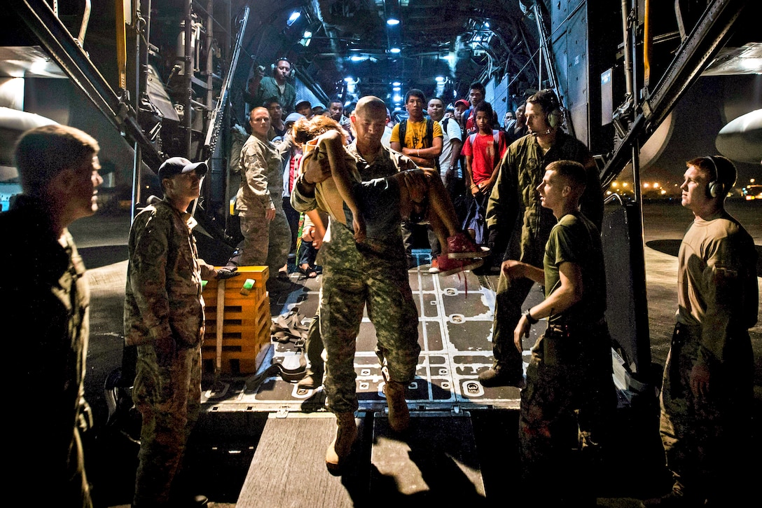 U.S. Air Force personnel help families in Ormoc affected by Typhoon Haiyan exit an MC-130 Combat Talon aircraft during Operation Damayan after transport to Manila, Philippines, Nov. 21, 2013.  