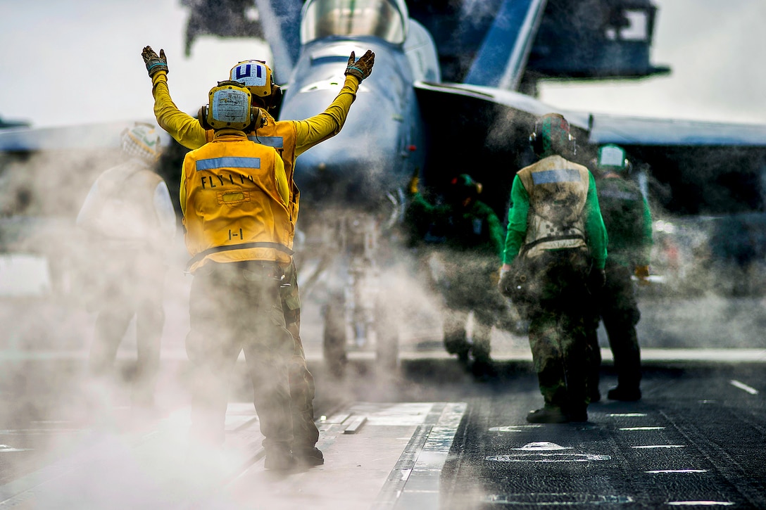 An aircraft handler directs an F/A-18 Super Hornet into position to launch from the flight deck of the aircraft carrier USS George Washington in the South China Sea, Nov. 5, 2013. The Washington and its embarked air wing, Carrier Air Wing 5, provide a combat-ready force to protect and defend the maritime interests of the U.S. and its allies and partners in the Indo-Asia-Pacific region.  