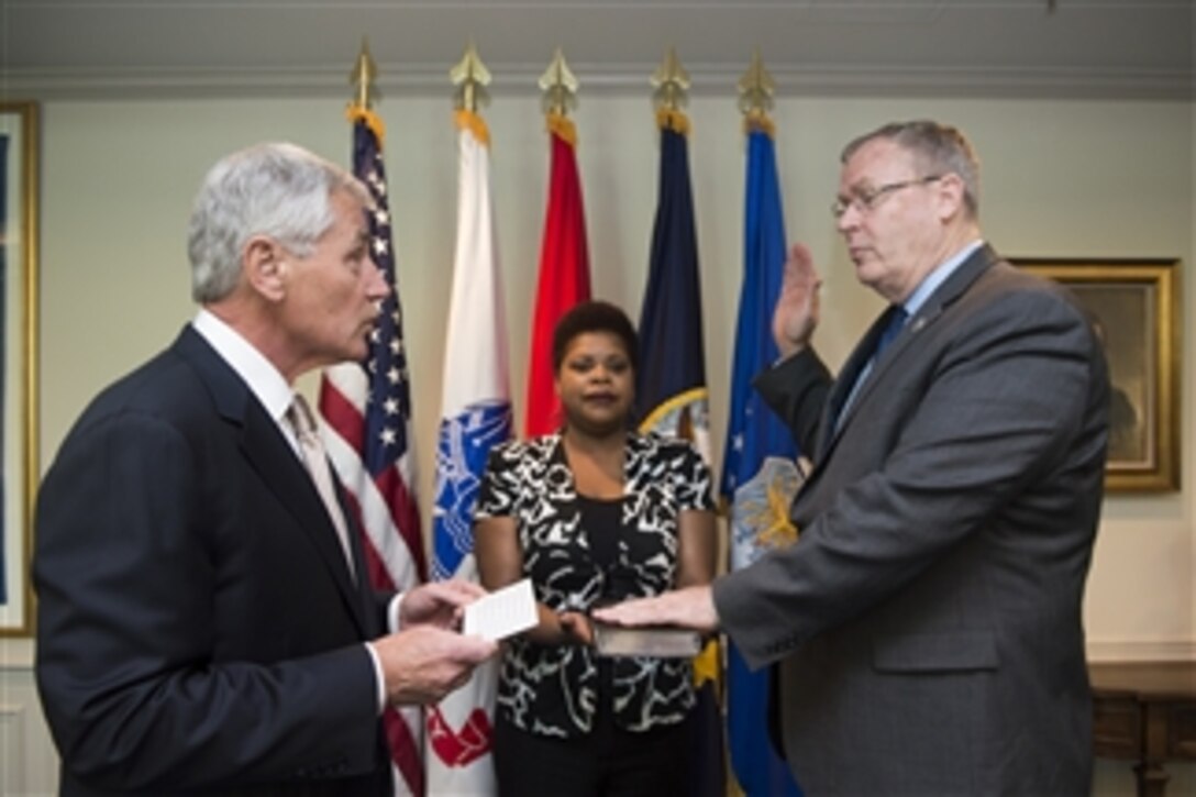 Defense Secretary Chuck Hagel, left, swears in new Deputy Defense Secretary Bob Work at the Pentagon, May 5, 2014. Caroline Wilson, Work's confidential assistant, held the Bible.