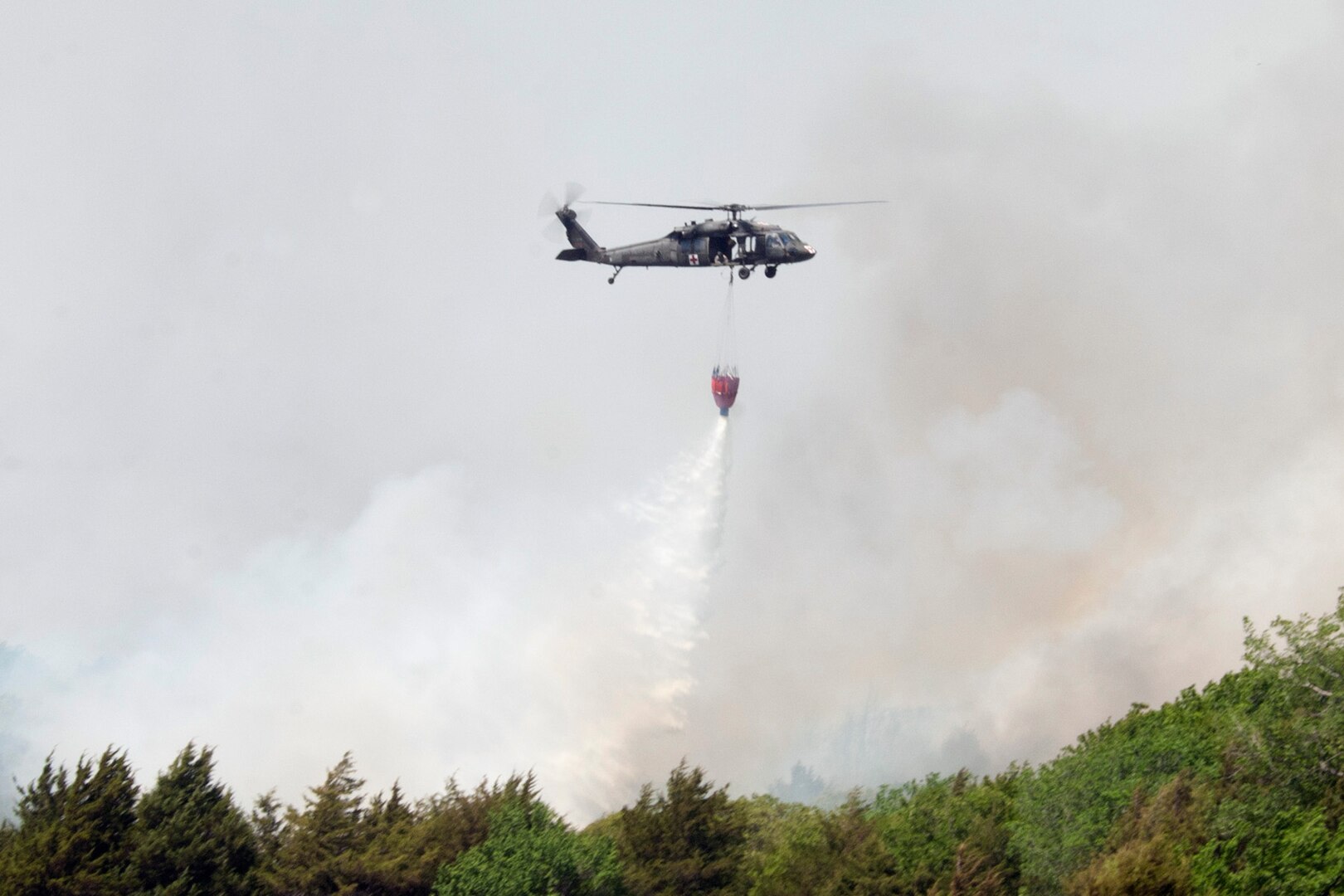 A UH-60 Black Hawk helicopter from the Oklahoma Army National Guard assists local firefighters near Guthrie, Oklahoma, as they attempt to contain wildfires that claimed more than 6,000 acres of land and numerous homes in less than 24 hours. The Blackhawks can carry 660 gallons of water in their "Bambi Bucket" which they refill in ponds and reservoirs. 