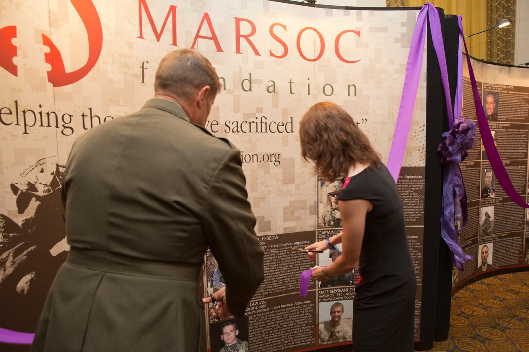 Major Gen. Mark A. Clark, commanding general of U.S. Marine Corps Forces Special Operations Command, and Sarah Christian, director of operations for the MARSOC Foundation cut a purple ribbon unveiling the MARSOC Foundation travel memorial wall, during ‘Honor the Fallen,’ a one-of-a-kind event, April 25, to honor all Marines, sailors and civilian Marines lost at home and abroad since MARSOC’s inception. The significance of the mobile memorial wall is to honor the Marines, sailors and civilian Marines who lost their lives while serving with MARSOC, as well as to honor their families, sharing their stories with as wide of an audience as possible. “The hope is that people will see the wall, reflect upon the service and sacrifice of these men & women and their families, and hopefully try to learn more about each of them,” said Christian.  “The MARSOC Foundation also hopes that it will remind the American public that even though military missions are not being talked about on the news, there are still brave men and women stationed throughout the world protecting our country and our freedom.”
