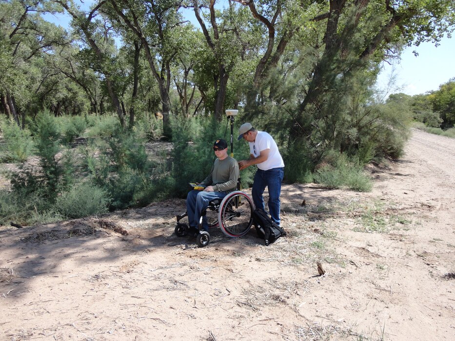 BERNALILLO COUNTY, N.M., -- Albuquerque District employee Ronnie Casaus sets up survey equipment on Bryan Estvanko’s off-road wheelchair to survey material quantities on the Rio Grande Bosque Levee on Sept. 23, 2012. Photo by Gary Edwards.