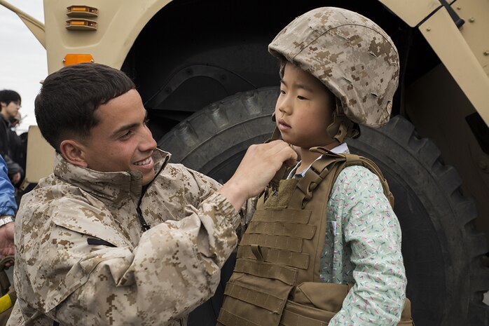 Cpl. Jose Escribano puts a Kevlar helmet onto a Japanese boy during Friendship Day at Marine Corps Air Station Iwakuni, Japan, May 5, 2014. Escribano is a motor transportation operator with Marine Wing Support Squadron 171, and was just one of the many Marines that helped host more than 50,000 visitors. Friendship Day is an event that allows Japanese citizens a chance to see military vehicles and aircraft, meet American service members and get a taste of American culture.