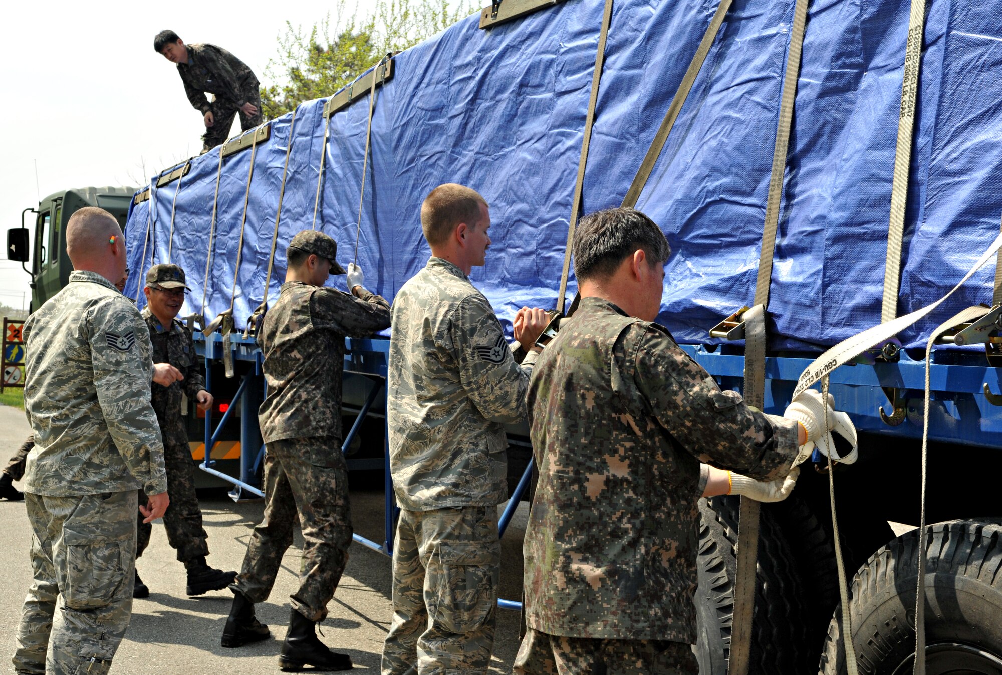 Airmen from the U.S. and Republic of Korea Air Forces cinch tie-down straps to secure a load of crates of LUU-2 aircraft illumination flares at the Alpha Site munitions storage area outside Osan Air Base, ROK, May 2, 2014. Osan worked with the ROKAF to stage 936 of the flares in Sacheon to support the ongoing search and rescue efforts for survivors of the Sewol ferry sinking. (U.S. Air Force photo/Airman 1st Class Ashley J. Thum)