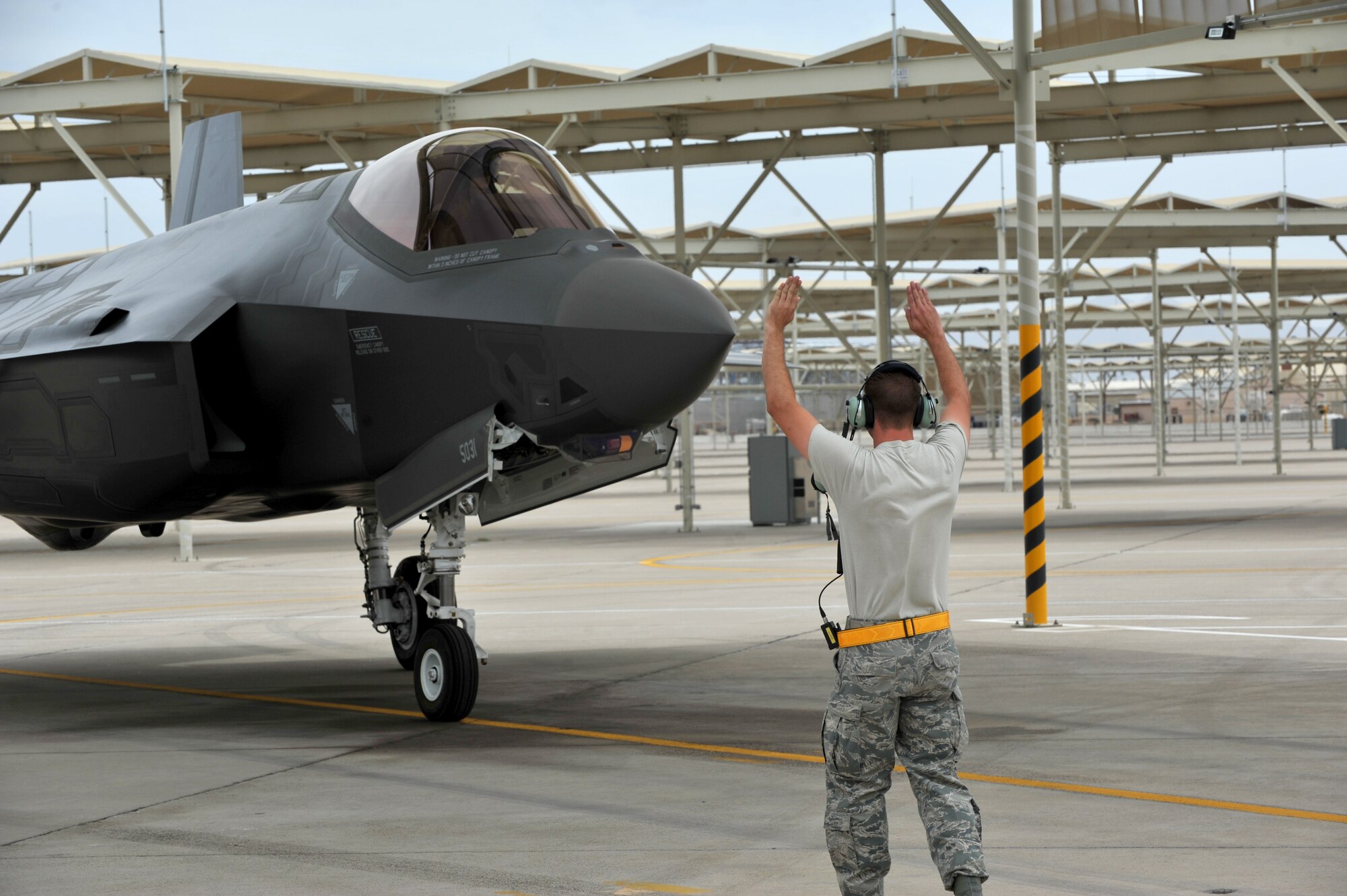 Senior Airman Paul Swanson, 61st Aircraft Maintenance Unit crew chief, marshals in one of Luke Air Force Base’s F-35 Lightning II after one of its first sorties May 6, 2014. (U.S. Air Force photo by Senior Airman Jason Colbert)