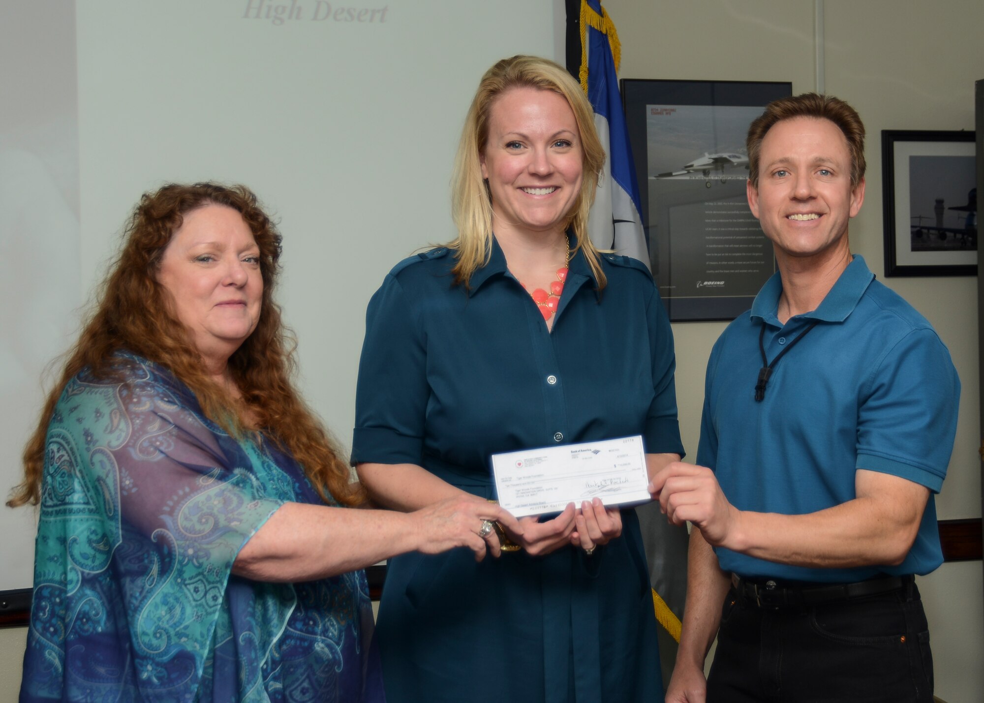 Tom Armfield (right) and Leslie Willhite (left), Boeing High Desert Employees Community Fund board members, present Jessica Carbajal,Tiger Woods Foundation, Development and Community Affairs director, a check to send five students of active duty military families to a Science Technology Engineering and Mathematics Summer Camp. (U.S. Air Force photo by Rebecca Amber)