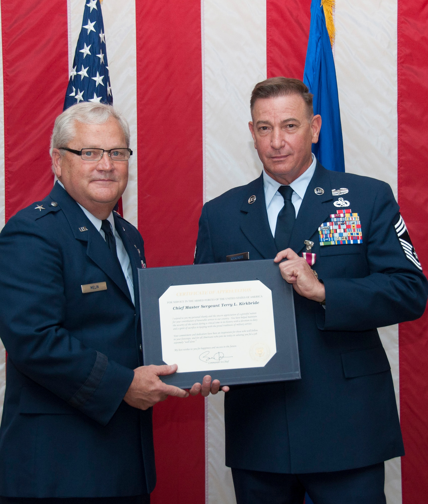 TRAVIS AIR FORCE BASE, Calif. -- Retired Brig. Gen. James Melin presents Chief Master Sgt. Terry Kirkbride with the meritorious service medal during a retirement ceremony April 26, 2014, at Travis Air Force Base, Calif. Kirkbride, who spent his entire Air Force career at Travis, retired as the 349th Maintenance Squadron superintendent. (U.S. Air Force photo/Master Sgt. Rachel Martinez)