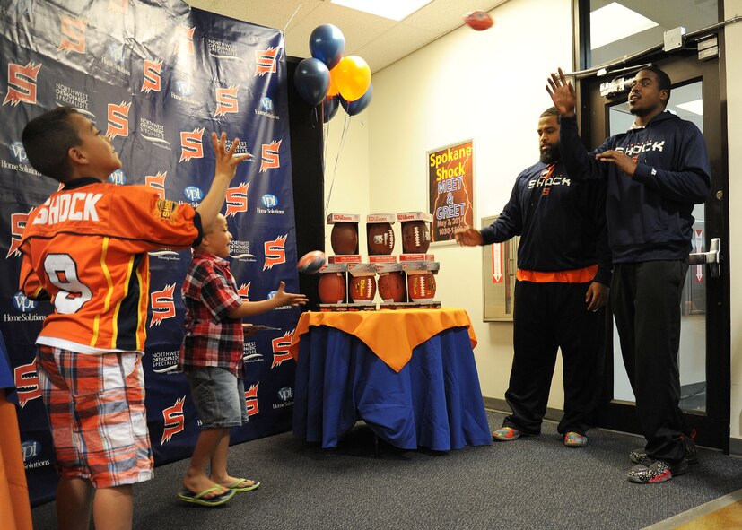 Spokane Shock arena football players play catch with kids during the meet and greet in the Exchange at Fairchild Air Force Base, Wash., May 2, 2014. The players gave out autographed shirts, calendars, key chains and more for fans to keep. (U.S. Air Force photo by Airman 1st Class Janelle Patiño/Released)