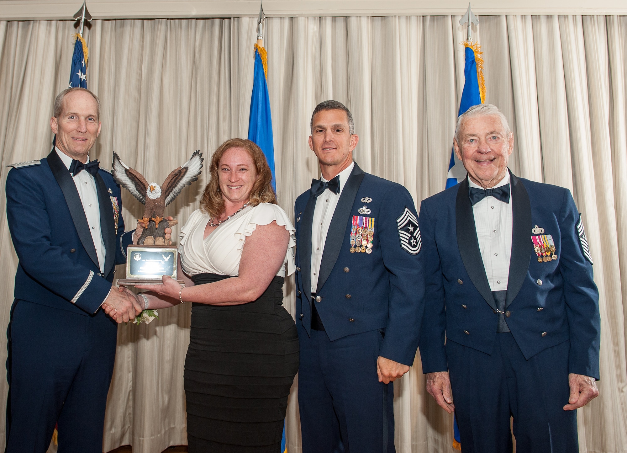 Master Sergeant Robert P. Mediavilla’s wife accepts his ACC Outstanding Airman of the Year award on his behalf, while he is deployed, at the Langley Club on Joint Base Langley-Eustis 23 April. (U.S. Air Force photo by Sachel Simone/Released) 