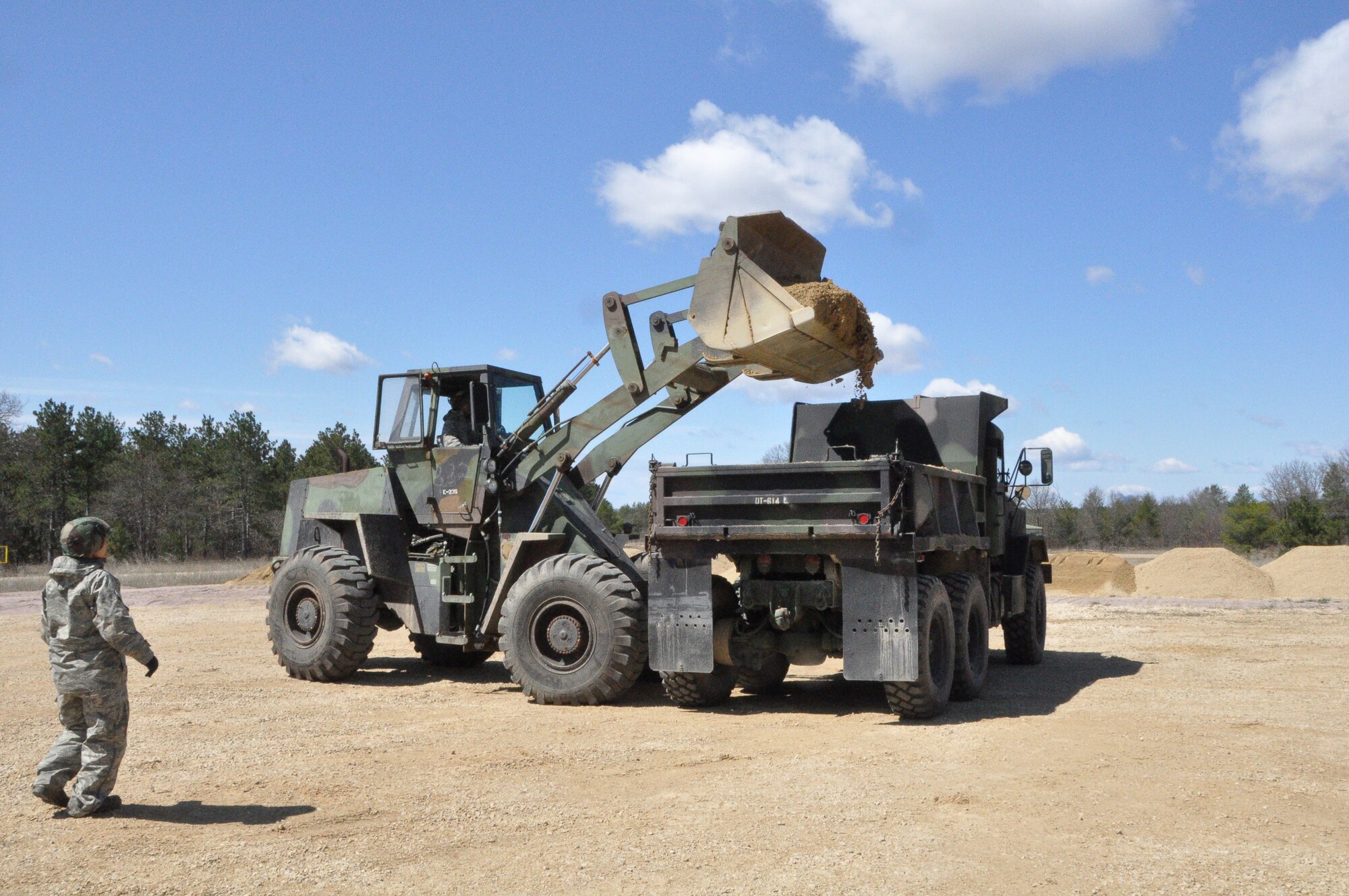 Staff Sgt. Corina Thornton, a 433rd Civil Engineer Heating Ventilation and Air Conditioning specialist, directs Senior Airman Sam Fernandez, (TITLE) as he loads the base for leveling the road at a rock quarry on Fort McCoy, Wisconsin May 3. These Air Force Reservists arrived here April 26 to bed down a Forward Operating Base, and are now helping with real world projects as the CE unit moves into the sustainment phase of Exercise Patriot Warrior. (U.S. Air Force photo by 1st Lt. Denise Haeussler)
