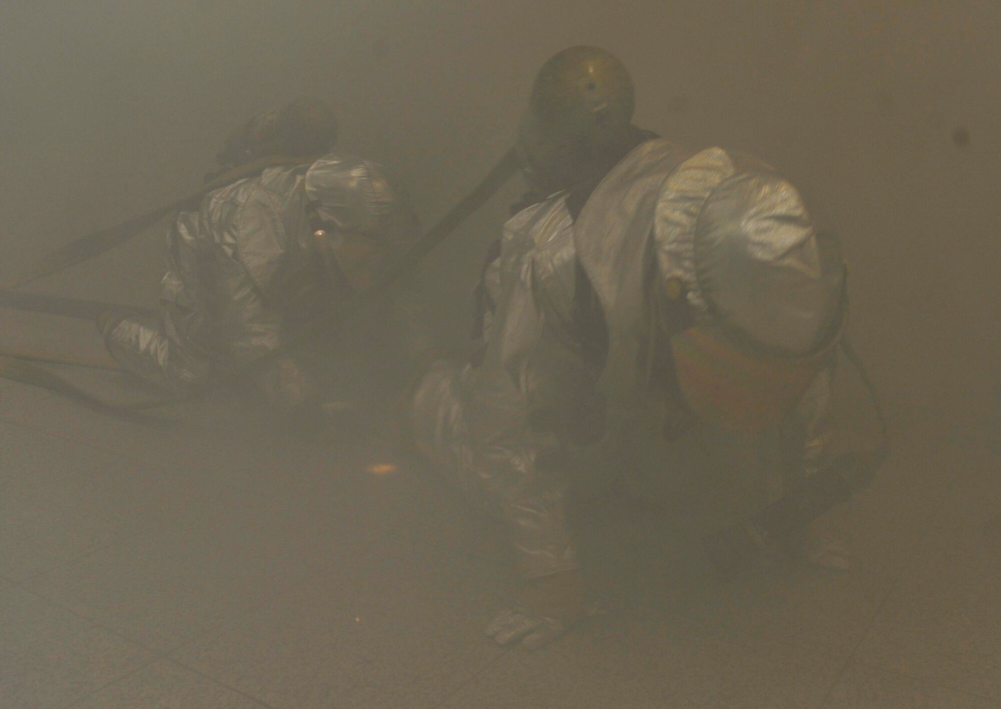 Firefighters crawl through the base passenger terminal as they search for the fire and injured personnel May 6 during a simulated missile attack scenario on Osan Air Base, Republic of Korea. The scenario caused a fire in the building and turned into a mass casualty event. (U.S. Air Force photo by Senior Airman David Owsianka)