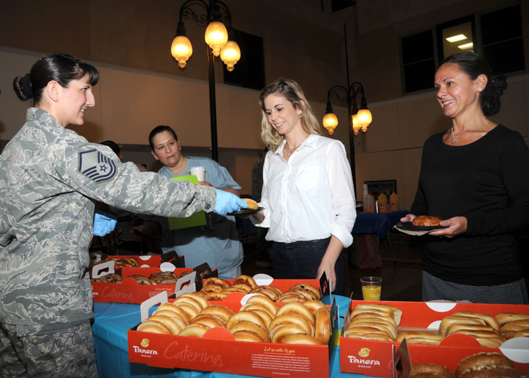 Master Sgt. Tiffany Mapes, 59th Medical Operation Squadron functional senior manager, serves bagels to Heather Freiermuth and Kimberly Bullock, both Family Health Department registered nurses, during the National Nurse Technician Week kick-off event, May 5, 2014 at the Wilford Hall Ambulatory Surgical Center, Joint Base San Antonio-Lackland. The annual event is an important part of the Total Nursing Force team which recognizes the roles and exceptional contributions of medical technicians in this week-long observance; it will conclude with a tribute to Florence Nightingale who is widely considered the founder of modern nursing. (U.S. Air Force photo/Harold China)