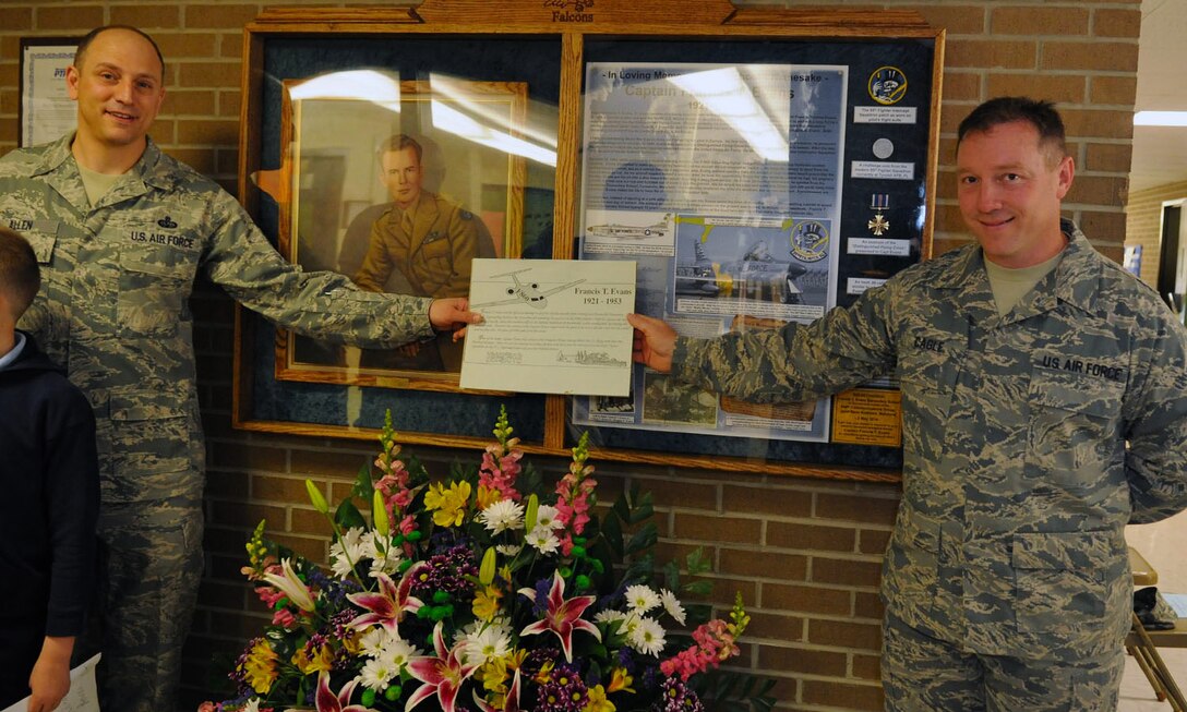 Master Sgts. Phillip Allen and Matt Cagle, 744th Communication Squadron plans and program managers, hold up the former memorial display in front of the newly dedicated memorial display case specially made for the Francis T. Evans Elementary School May 2, 2014. The case displays memorabilia of the school’s namesake, Capt. Francis T. Evans, Jr. and is located at the school just outside of Joint Base Andrews, Md. (U.S. Air Force photo/Aimee Fujikawa)