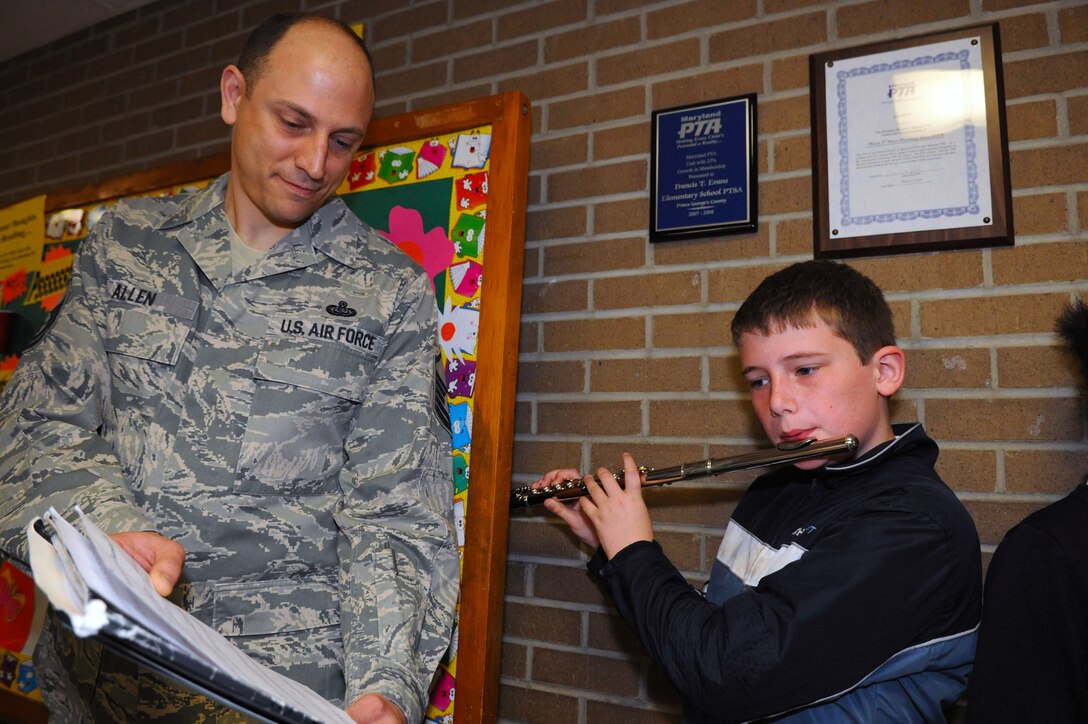 Master Sgt. Phillip Allen, 744th Communication Squadron plans and program manager, holds a music sheet for flutist, Peter Morgera, a fifth-grade student at the Francis T. Evans Elementary School during a dedication ceremony May 2, 2014. The case displays memorabilia of the school’s namesake, Capt. Francis T. Evans, Jr. and is located at the school just outside of Joint Base Andrews, Md. (U.S. Air Force photo/Aimee Fujikawa)

