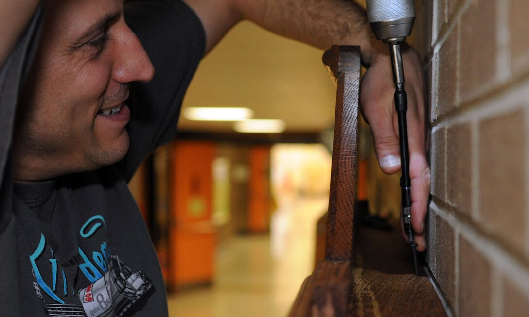 Master Sgt. Phillip Allen, 744th Communication Squadron plans and program manager, attaches the final screw to mount a memorial display case at the school May 1, 2014. The case displays memorabilia of the school’s namesake, Capt. Francis T. Evans, Jr. and is located at the school just outside of Joint Base Andrews, Md. (U.S. Air Force photo/Aimee Fujikawa)