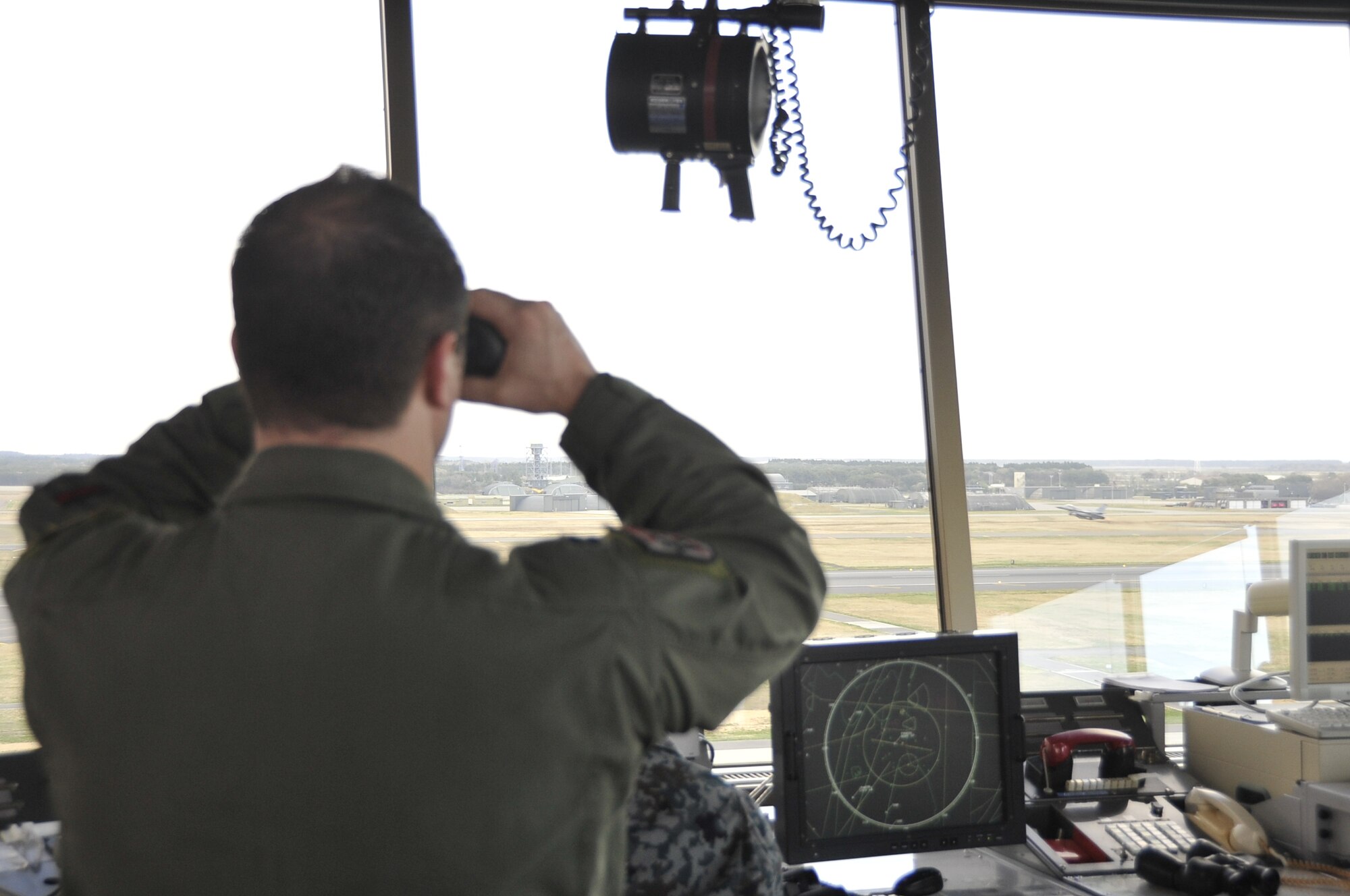 U.S. Air Force Capt. Christian Hamilton, 35th Operations Support Squadron aircrew flight equipment flight commander and supervisor of flight officer, watches the arrival of an F-16 Fighting Falcon, ensuring its’ safe landing. The SOF works in tandem with the Japan Air Self-Defense Force air traffic control team to monitor the status of incoming and outgoing aircraft. (U.S. Air Force photo/Airman 1st Class Patrick Ciccarone)