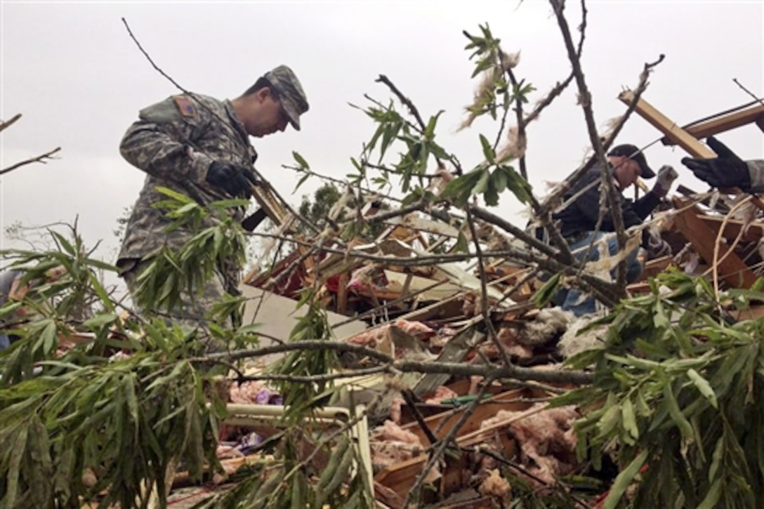 An Arkansas Guardsman searches through piles of debris for possible survivors in Vilonia, Ark., April 28, 2014, in the wake of a killer tornado that struck April 27 in the small central Arkansas towns of Vilonia and Mayflower. By the next day, the Arkansas National Guard had 60 Guardsmen on state active duty to work recovery and relief efforts.  