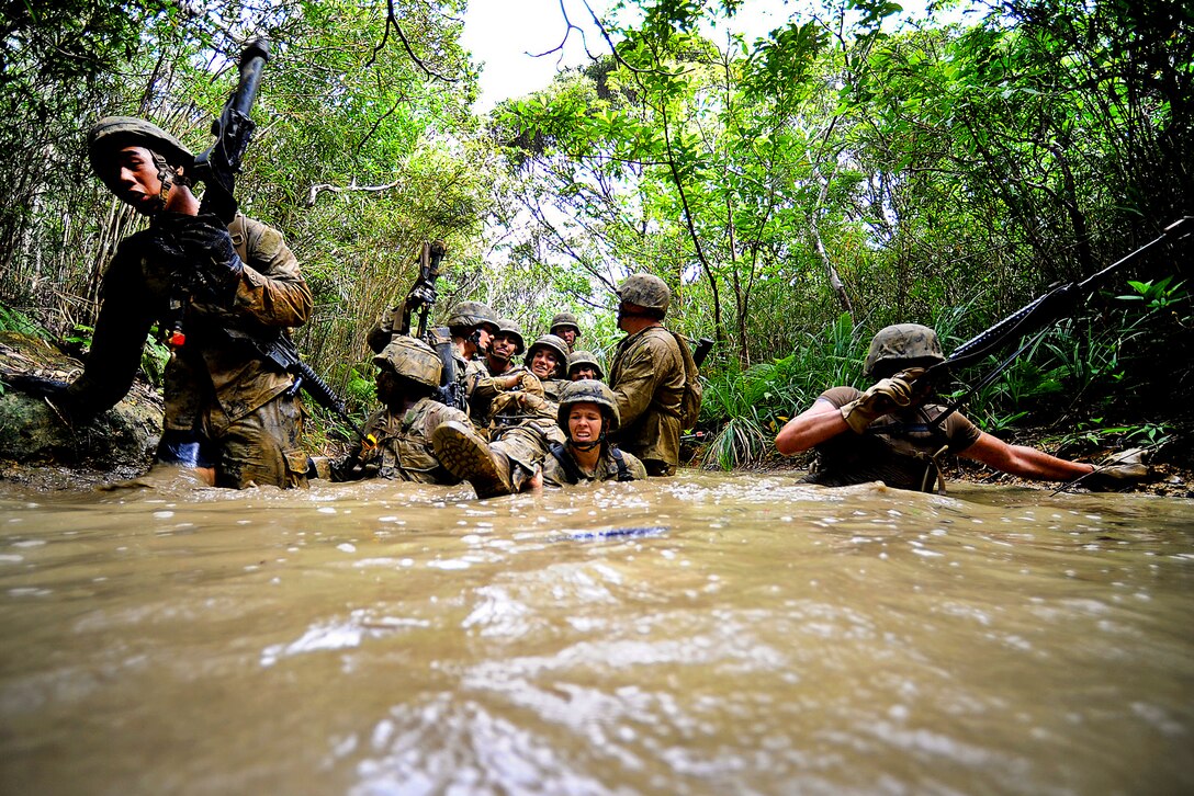 U.S. Navy Seabees carry a mock casualty on an improvised stretcher through shoulder-high muddy water while running a six-hour endurance course at the Marine Corps Jungle Warfare Training Center in Okinawa, Japan, Sept. 22, 2013. More than 60 Seabees attended the eight-day course.  
