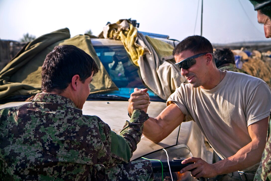 U.S. Army Spc. Nathan B. Joachim, right, and an Afghan soldier engage in a friendly competition of arm wrestling after a mission on Combat Outpost Kaligu in Afghanistan, Sept. 13, 2013. Joachim, an infantryman, is assigned to the 101st Airborne Division's Company D, 1st Battalion, 506th Infantry Regiment, 4th Brigade Combat Team.  
