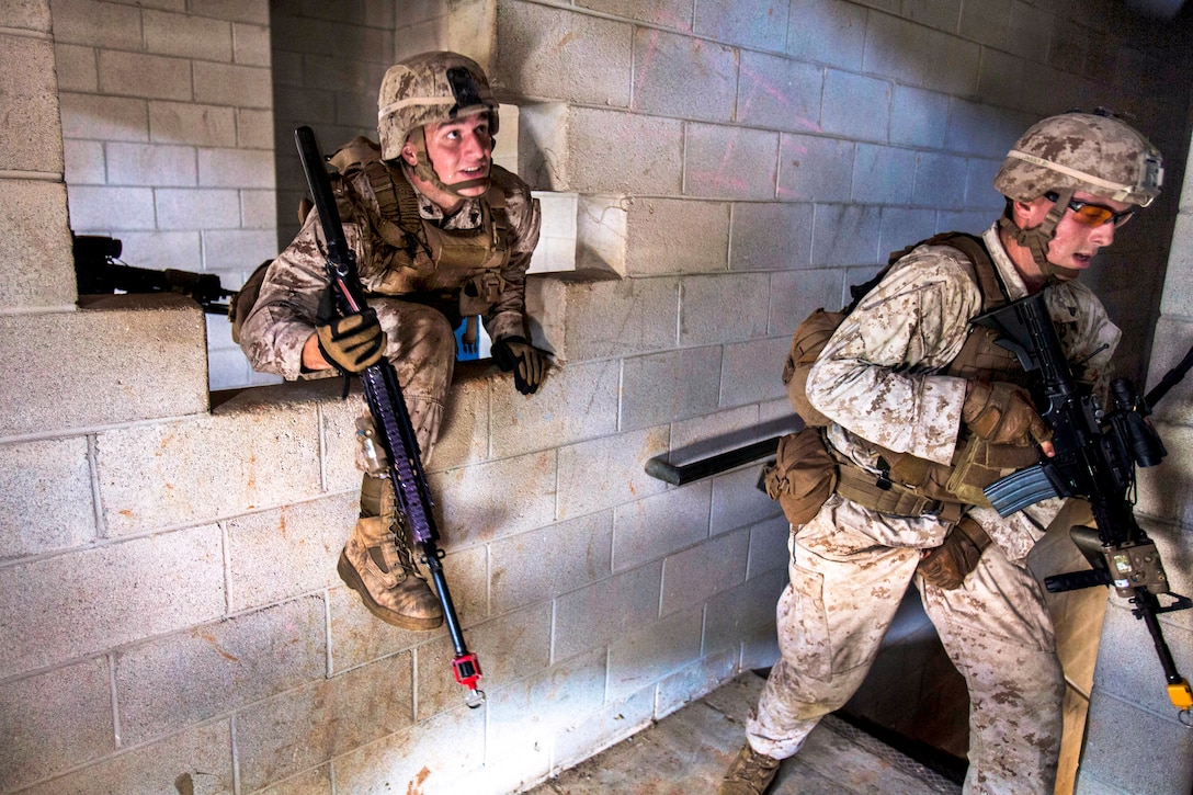 Marine Corps Cpl. David Rodriguez, left, fire team leader, climbs through a hole as his fire team clears a building while conducting a platoon-sized raid on a simulated town during urban tactics training on Fort Pickett, Va., Aug. 30, 2013. Rodriguez, a fire team leader, is assigned to Battalion Landing Team, 1st Battalion, 6th Marine Regiment, 22nd Marine Expeditionary Unit. 
