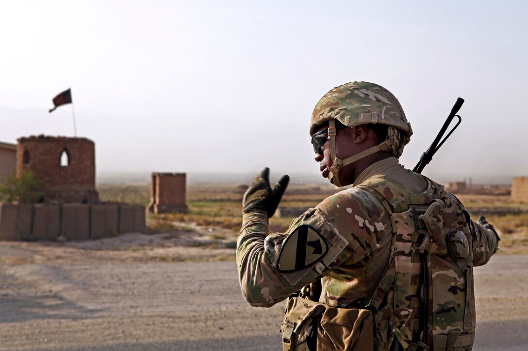 U.S. Army Pfc. Shan Lawrence directs the flow of traffic during an entry control stop across from the Afghan national police station in Qarabagh, Afghanistan, Aug. 24, 2013. Lawrence is assigned to 3rd Battalion, 82nd Field Artillery Regiment.  
