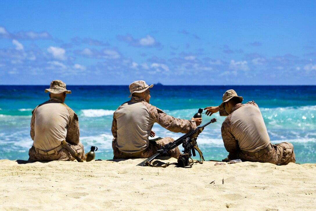 Marines enjoy a moment of relaxation on a beach after conducting an amphibious training raid as part of Tropic Thunder, an exercise on Marine Corps Base Hawaii, Kaneohe Bay, Hawaii, Aug. 30, 2013.  
