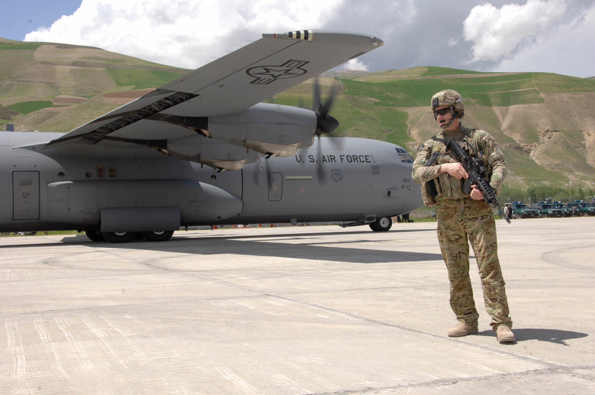 Airman 1st Class Sergio Mihai stands guard May 5, 2014, as a C-130J-30 is unloaded with personnel and supplies at Fayzabad Airport. Coalition Forces to include an Italian C-130 and a crew assigned to the 774th Expeditionary Aerial Squadron assisted the Afghan Government with relief efforts after a recent mudslide in Badakhshan province. Mihai is a fly away security team member assigned to the 455th Expeditionary Base Defense Squadron at Bagram Airfield, Afghanistan. (U.S. Air Force photo/Master Sgt. Cohen A. Young)