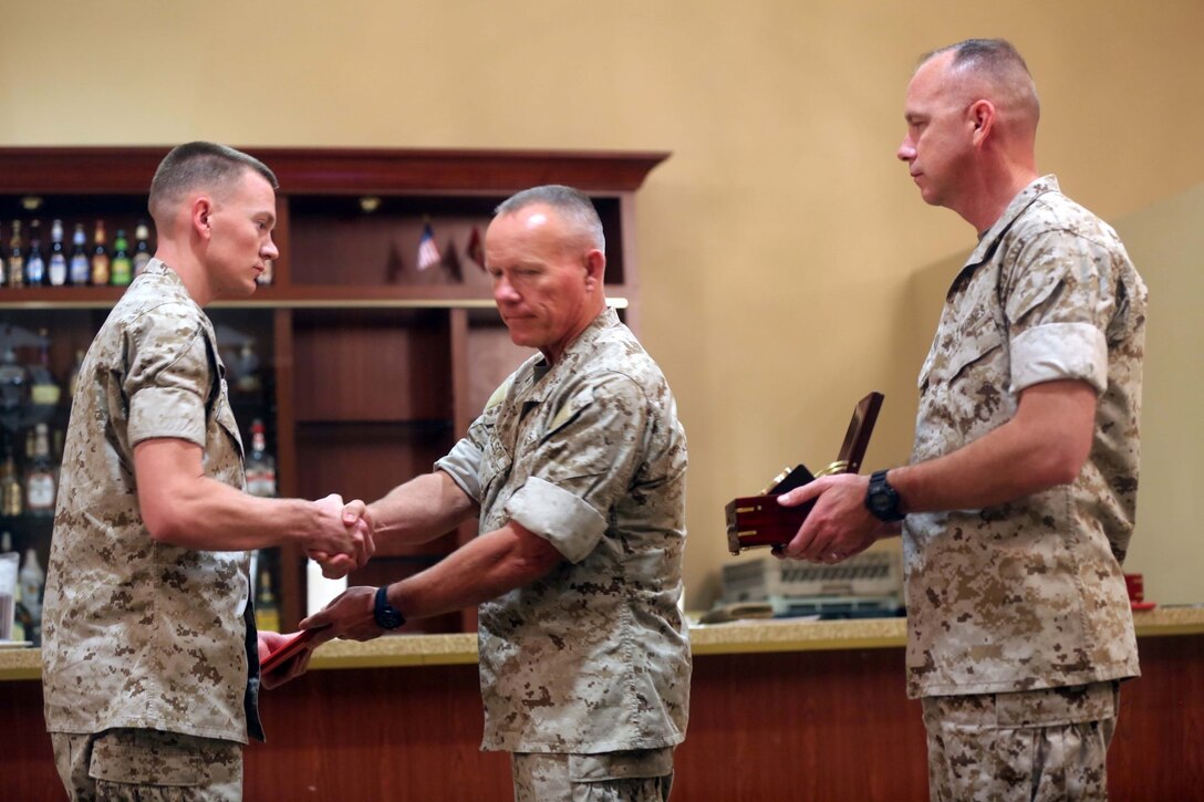 Major Gen. Lawrence D. Nicholson, center, the commanding general of 1st Marine Division, awards Cpl. Jager Hibler, left, a motor transportation operator with 3rd Combat Engineer Battalion, the 2013 Marine Corps Motor Transport Association’s Operator of the Year award during an award ceremony aboard Marine Corps Base Camp Pendleton, Calif., April 30, 2014. Hibler, a 22-year-old native of Alamogordo, N.M., has traveled 1,500 miles throughout combat zones in Helmand province, Afghanistan, where he transported personnel and key equipment across his area of operations.