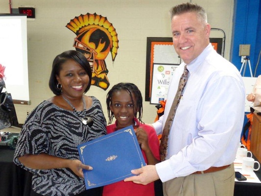 Michael Steele, executive principal at Stratford STEM Magnet High School, presents a community service award May 5, 2014 to Stephanie Coleman, an Equal Employment Opportunity specialist, who accepted on behalf of the U.S. Army Corps of Engineers Nashville District. The school used the event at the high school to highlight the contributions of its partners that contribute to the success of the school and its focus on science, technology, engineering and mathematics. Coleman’s son joined her in the photo.