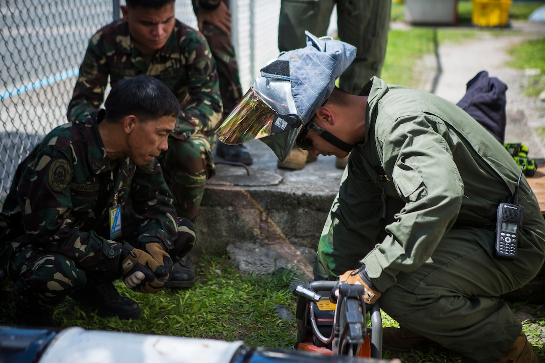 Philippine Air Force TSg Ronnie G. Angara, a fire protection apprentice, with 6012th Base Operations Squadron, 600th Air Base Wing, stationed at Clark Air Base, observes as U.S. Marine Corps Lance Cpl. David D. Enriquez, air rescue firefighting, with Marine Wing Support Squadron 172, Marine Aircraft Group 36, 1st Marine Air Wing, stationed at Camp Foster, Okinawa, Japan, demonstrates how to operate a K12 Rescue Saw for extraction equipment training during Balikatan 2014 at Clark Air Base, Mabalacat, Republic of the Philippines, May 6, 2014. This year marks the 30th iteration of Balikatan, which is an annual Republic of the Philippines-U.S. military bilateral training exercise.