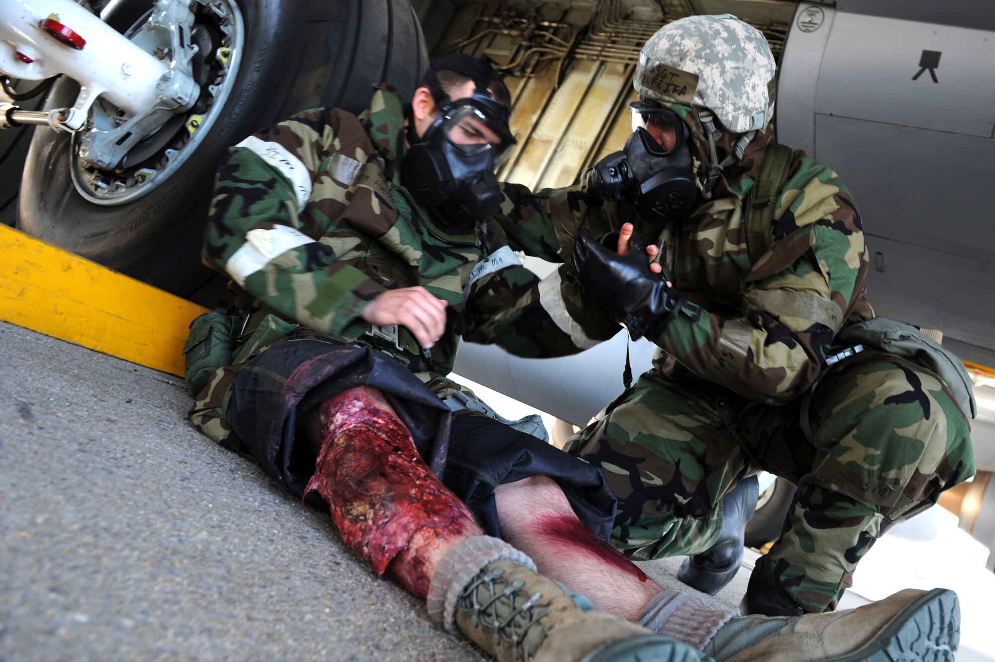 Staff Sgt. Juan Azofeifa, 22nd Aircraft Maintenance Squadron crew chief, performs self aid buddy care on Senior Airman Brandon Hunter, 22nd AMXS electric environmental specialist, who has simulated wounds on his legs, May 6, 2014, at McConnell Air Force Base, Kan. This kind of training is designed to prepare Airmen for possible combat scenarios. (U.S. Air Force photo/Airman 1st Class Aaron-Forrest Wainwright) 